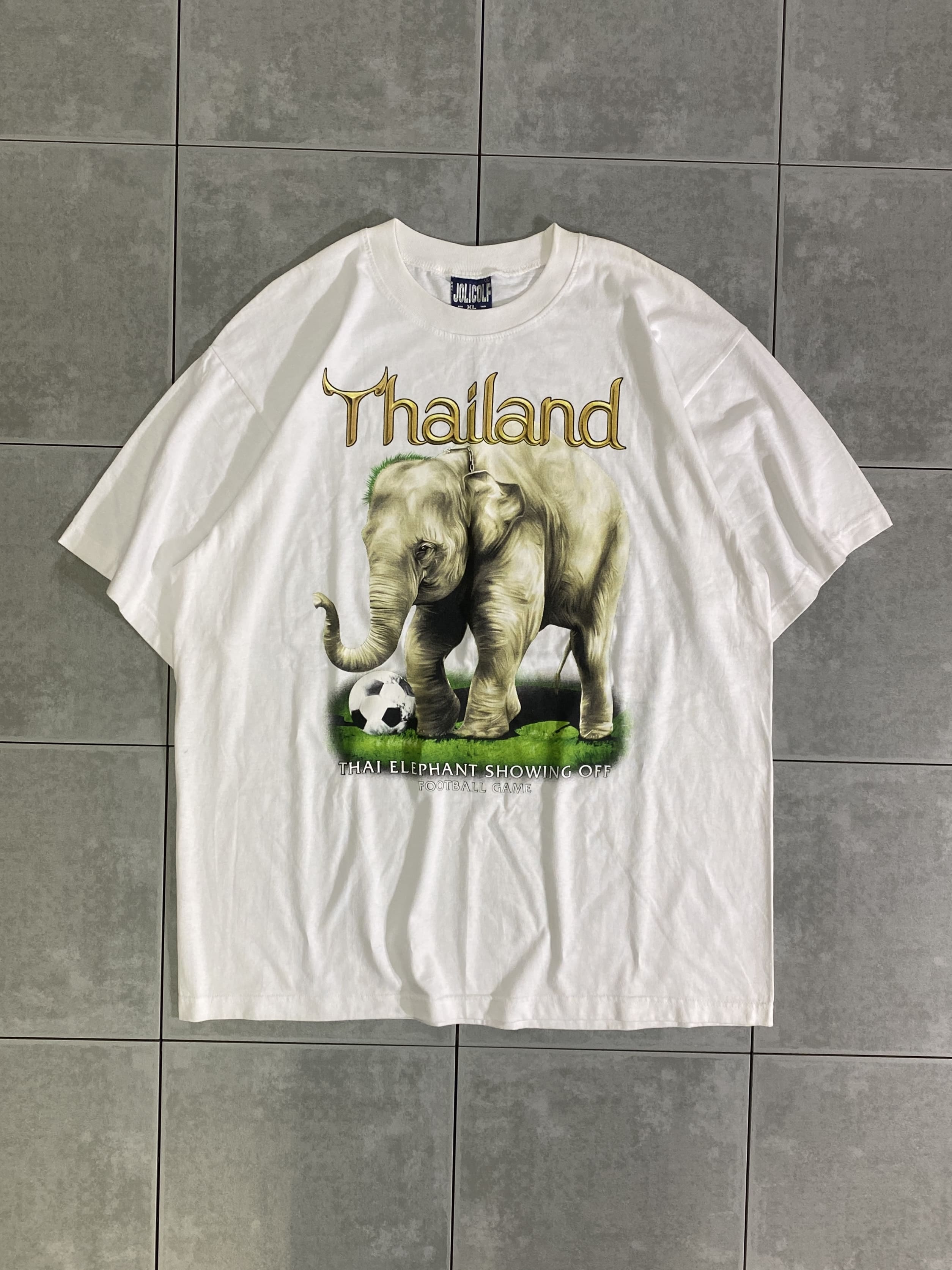 JOLIGOLF

【JOLIGOLF】THAILAND S/S TEE

カラー：ホワイト

サイズ：XL
着丈：約75cm　身幅：約62cm　肩幅：約57cm　袖丈：約24cm

素材：コットン100％

JOLIGOLFのプリントTシャツ。

フロント一面に大きく映った象のプリントが目を惹く一枚。

サイズ感かなり大きめです。

夏の装いに、インパクトを与えてくれるアイテムです。

※画像の程度とは若干異なる場合がございますので予めご了承下さい。
(キズ、へこみ、汚れ、穴あき、ほつれ、文字書入れ(名前、ナンバー)など

