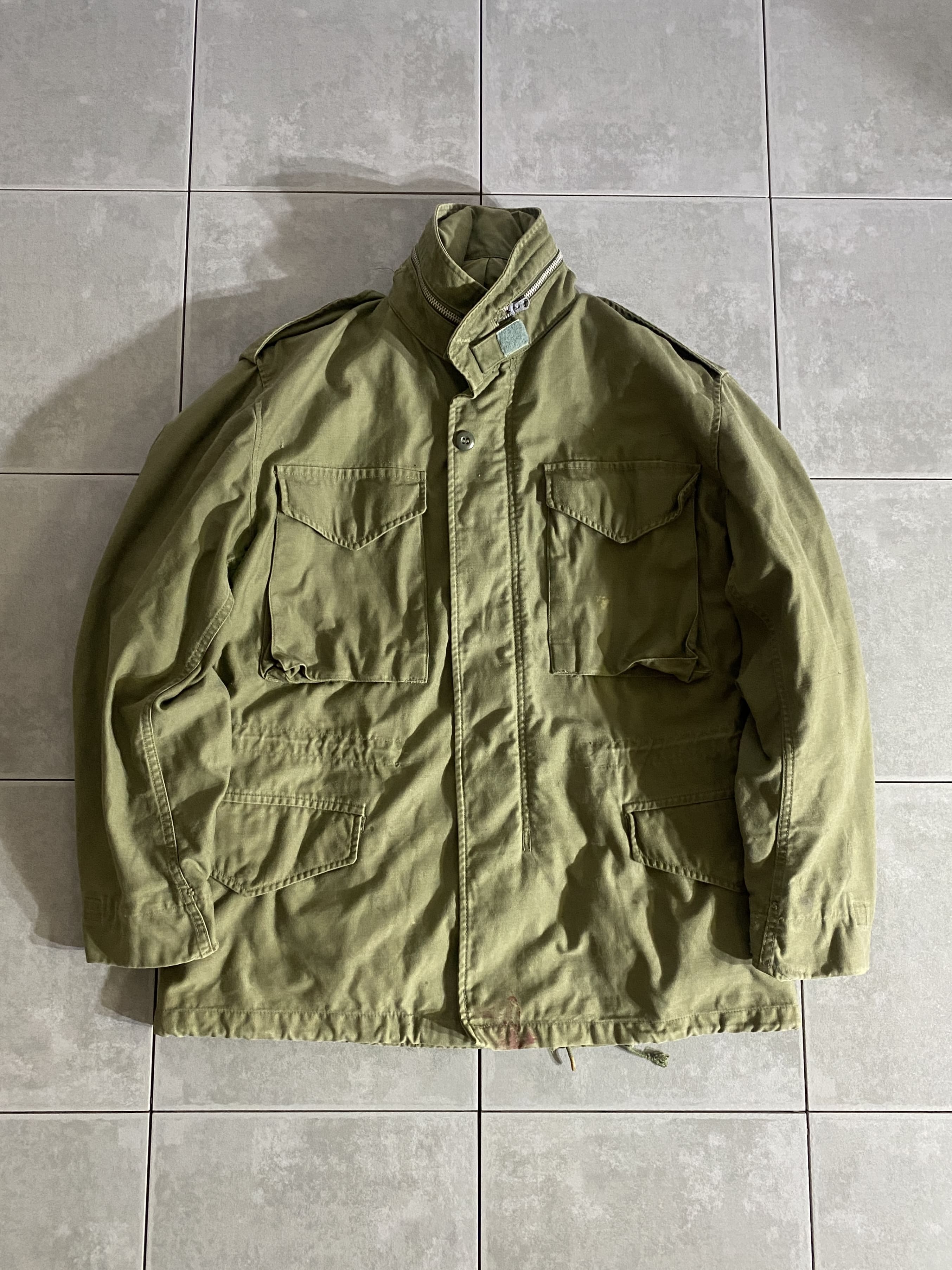 米軍放出品

M-65 FIELD JACKET 2nd Model

カラー：OD

サイズ：S-S
着丈：約73cm　身幅：約56cm　肩幅：約50cm　袖丈：約60cm

素材：コットン　ナイロン

TALON ZIP

米軍が開発したミリタリーアイテムの中で最高傑作ともいえる
M-65 FIELD JACKET。

ミリタリーを語る上で外せないアイテムです。

一般にファーストタイプ、アルミジッパータイプと呼ばれるのが、
この2nd Modelになります。

収納式フード、肩にはエポレット付きで
フロント部分はジッパーとスナップボタンで開閉できます。

目立ったダメージもないグッドコンディションです。

ODは特に放出がなく年々希少価値が上がっているので
今のうちに買っておくのがオススメです。

※画像の程度とは若干異なる場合がございますので予めご了承下さい。
(キズ、へこみ、汚れ、穴あき、ほつれ、文字書入れ(名前、ナンバー)など

