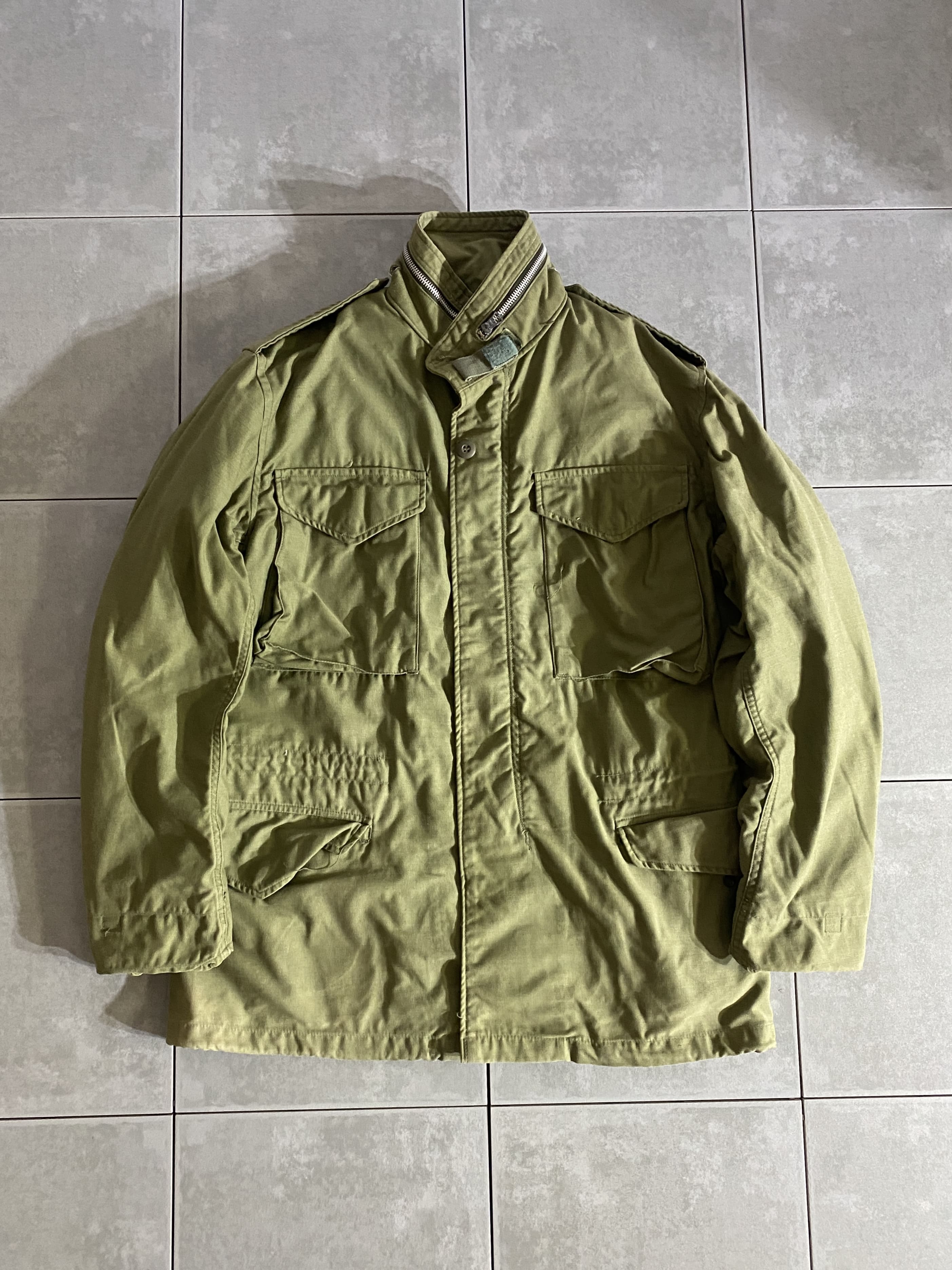 米軍放出品

60s M-65 FIELD JACKET 2nd Model

カラー：OD

サイズ：S-R
着丈：約76cm　身幅：約55cm　肩幅：約47cm　袖丈：約62cm

素材：コットン　ナイロン

SCOVILL ZIP

軍が開発したミリタリーアイテムの中で最高傑作ともいえる
M-65 FIELD JACKET。

ミリタリーを語る上で外せないアイテムです。

一般にファーストタイプ、アルミジッパータイプと呼ばれるのが、
この2nd Modelになります。

収納式フード、肩にはエポレット付きで
フロント部分はジッパーとスナップボタンで開閉できます。

目立ったダメージもないグッドコンディションです。

ODは特に放出がなく年々希少価値が上がっているので
今のうちに買っておくのがオススメです。

※画像の程度とは若干異なる場合がございますので予めご了承下さい。
(キズ、へこみ、汚れ、穴あき、ほつれ、文字書入れ(名前、ナンバー)など

