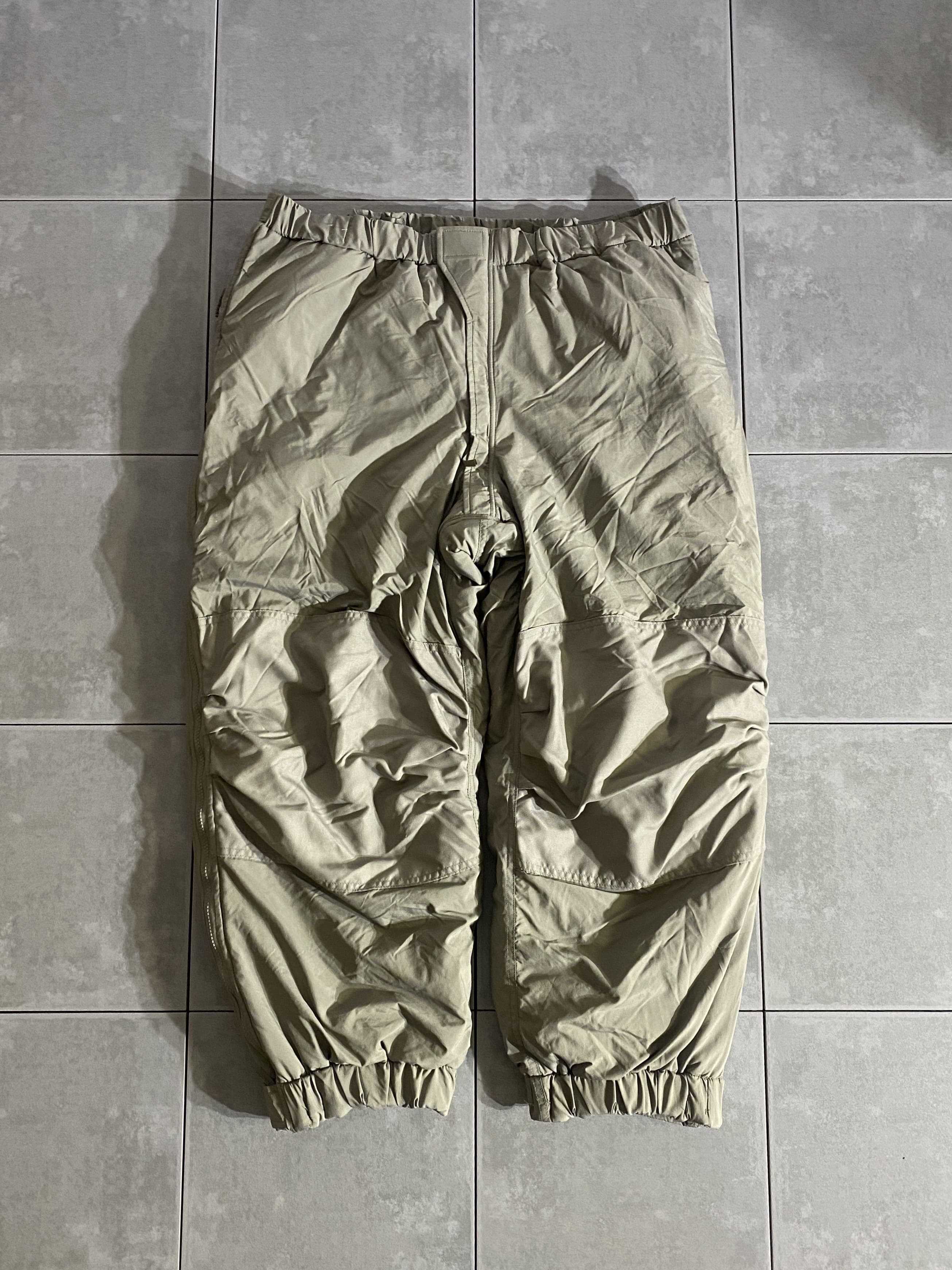 DEAD STOCK

ECWCS GEN III LEVEL7 PANTS PRIMALOFT

カラー：URBAN GREY

サイズ：L-R
ウエスト：約92-126cm　股下：約70cm　
もも幅：約38cm　総丈：約104cm

素材：ナイロン　中綿：プリマロフト

米軍実物デッドストックのLEVEL7パンツ。

ECWCS第三世代は7種類のトップスと5種類のボトムスから
構成された様々な環境、気候等に対応したレイヤリングシステムです。

LEVEL7はレイヤリング最終防寒アウターとして、
中綿にはPRIMALOFT(プリマロフト)を仕用。

ダウンウェアと違い、羽が飛び出したり手入れに手間がかかる事がなく、
洗濯機で洗えて軽量でやわらかな風合いが特徴。

両サイドフルオープンなので靴を履いたままでも脱ぎ履きができ、
防寒着としてはもちろん、スキーウェアとしても使用できます。

非常に人気が高く、入手困難なアイテム1つです。

※画像の程度とは若干異なる場合がございますので予めご了承下さい。
(キズ、へこみ、汚れ、穴あき、ほつれ、文字書入れ(名前、ナンバー)など