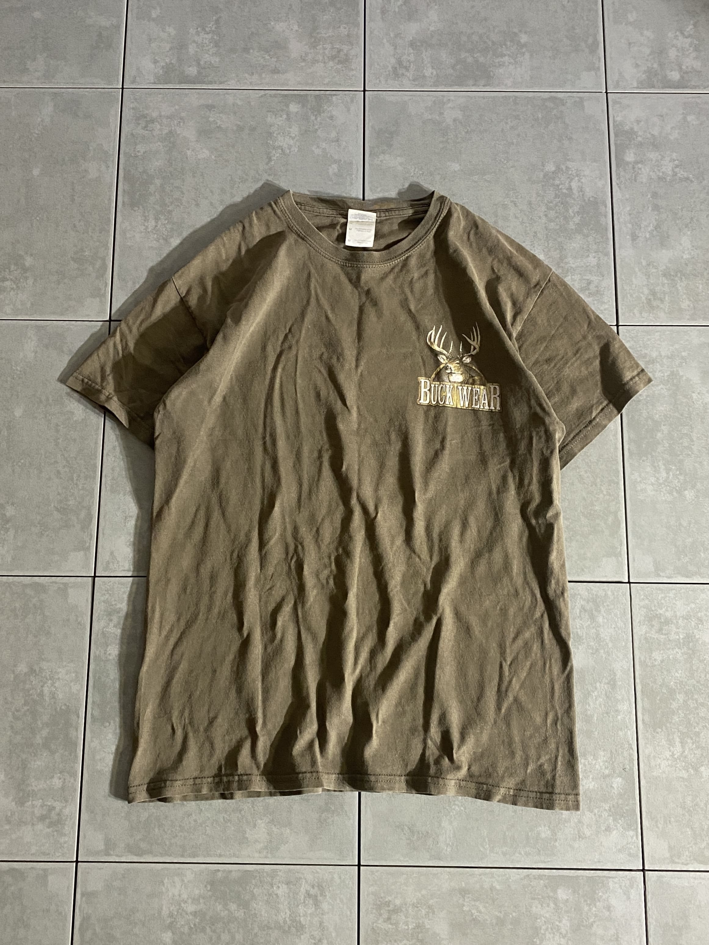 GILDAN

【GILDAN】BUCK WEAR S/S TEE

カラー：ブラウン

サイズ：M
着丈：約66cm　身幅：約50cm　肩幅：約48cm　袖丈：約17cm

素材：コットン

くすんだブラウンカラーの半袖Tシャツ。

フロント左胸にワンポイント、バックにプリントがございます。

※画像の程度とは若干異なる場合がございますので予めご了承下さい。
(キズ、へこみ、汚れ、穴あき、ほつれ、文字書入れ(名前、ナンバー)など

