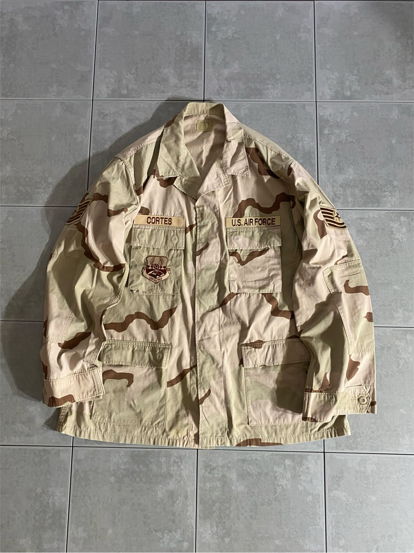 米軍放出品

3C Desert Camo DCU Jacket

カラー：3C

サイズ：XL-L
着丈：約83cm　身幅：約70cm　肩幅：約53cm　袖丈：約67cm

素材：コットン　ナイロン

リップストップ

1990年代初頭より全軍に採用されたDCUジャケット。

フロント4ポケットのBDUジャケットと同様のデザインで、
DCUいう3カラーで構成された迷彩柄。

砂漠地帯を対象として作成され、より有効性の高い
迷彩パターンとして採用されております。

ファッション性の高いデザインでミリタリーの
定番とも言えるジャケットです。

薄手で羽織りやすく、様々なスタイリングに合わせて
楽しんでいただけるアイテムです。

※画像の程度とは若干異なる場合がございますので予めご了承下さい。
(キズ、へこみ、汚れ、穴あき、ほつれ、文字書入れ(名前、ナンバー)など