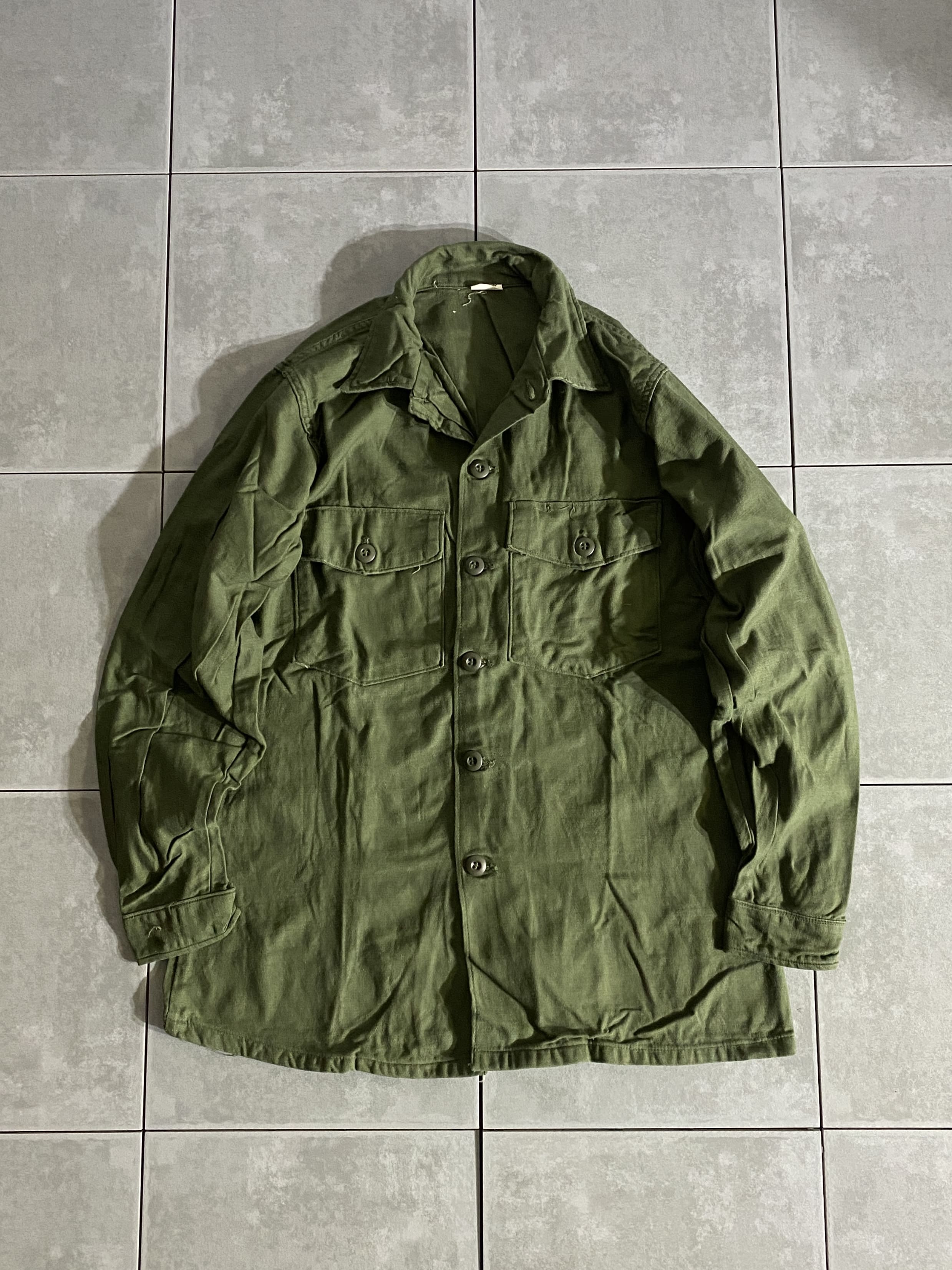 米軍放出品

60s Cotton Sateen Utility Shirt OG-107 シャツ袖2nd Model

カラー：OD

サイズ：15 1/2×33
着丈：約71cm　身幅：約54cm　肩幅：約40cm　袖丈：約60cm

素材：コットン

ミリタリーアイテムの中でも定番で人気のユーティリティシャツ。

1965年に筒袖からシャツ袖にモデルチェンジされ、
1年後の1966年に使用ボタンが平ボタンから
BDUボタンに変更されています。

1978年以降のコットンポリ素材のシャツとは違い、
着込むほどに風合いの良い経年変化も楽しめる素材です。

コンディションも良く、まだまだ楽しんでお使いいただけます。

※画像の程度とは若干異なる場合がございますので予めご了承下さい。
(キズ、へこみ、汚れ、穴あき、ほつれ、文字書入れ(名前、ナンバー)など