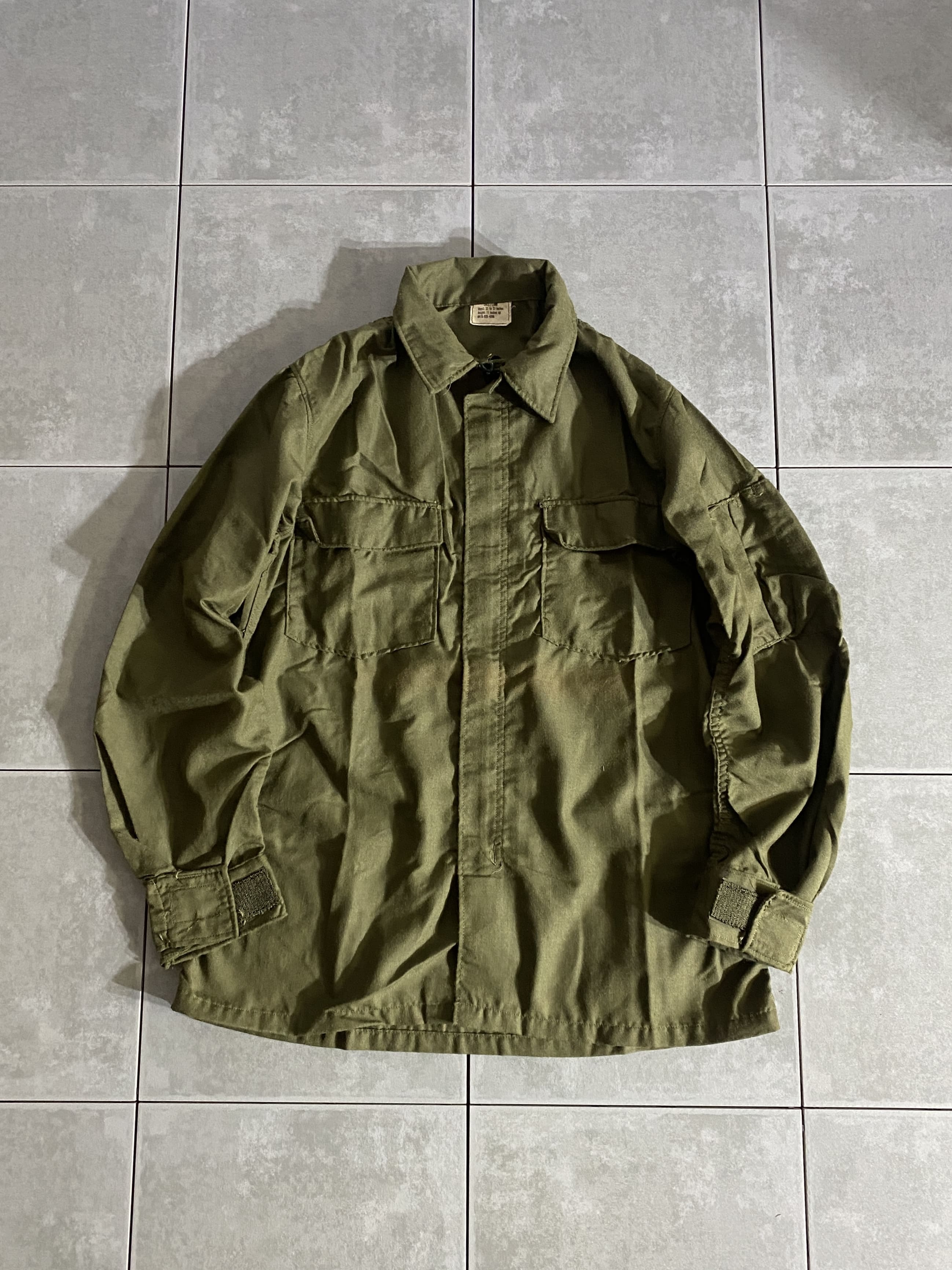 米軍放出品

70s NOMEX ヘリクルーシャツ

カラー：OD

サイズ：S-L
着丈：約72cm　身幅：約53cm　肩幅：約43cm　袖丈：約60cm

素材：ナイロン

SCOVILL ZIP

温暖な気候の地域にてヘリパイロットおよび搭乗員が着用する
ポリアミド製のヘリクルーシャツ。

アラミド繊維を使用したNOMEXタイプで、燃えにくい難炎性素材を
使用しながらも、かなり薄手でシャツや羽織としての使用も可能。

襟裏にはベルクロのチンストラップが付属しており、
スタンドカラーシャツとしても着用できます。

シャツとしてはもちろん、シャツジャケットとしても可能なアイテムです。

薄手なので幅広いシーズンお使いいただけます。

※画像の程度とは若干異なる場合がございますので予めご了承下さい。
(キズ、へこみ、汚れ、穴あき、ほつれ、文字書入れ(名前、ナンバー)など