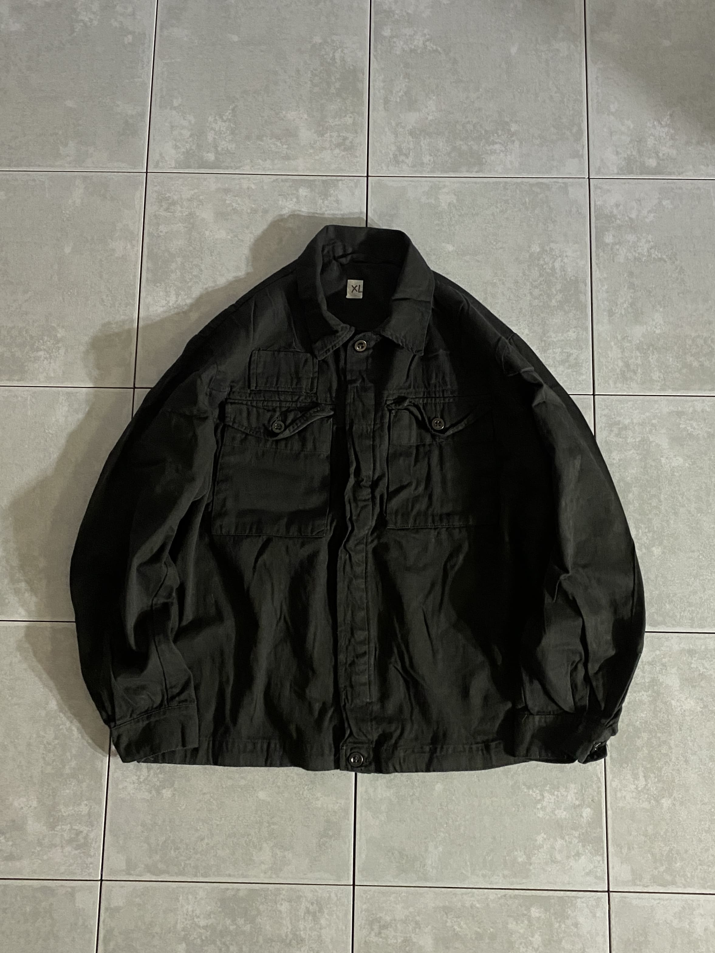 DEAD STOCK

チェコ軍 フライフロントワークシャツ BLACK染め

カラー：BLACK

サイズ：L / XL
  L 着丈:約60-68cm 身幅:約60-61cm 
     肩幅:約42-50cm 袖丈:約56-64cm

XL 着丈:約60-68cm 身幅:約62-63cm 
     肩幅:約42-50cm 袖丈:約56-64cm

素材：コットン

元々ライトブラウンだったシャツを染め職人が丁寧に
BLACK染めしております。

BLACKにする事で無骨さが増し、
合わせるインナーの幅も広がります。

前立てが2重のフライフロントで、中心部分4つのボタンが
表から見えないようにしたデザインが風の侵入を防ぐなどの
役割を果たす特徴的な1枚です。

ジャケット感覚でも着ていただけるデザインですので
様々な季節で使えるおすすめのユーロミリタリーです。
