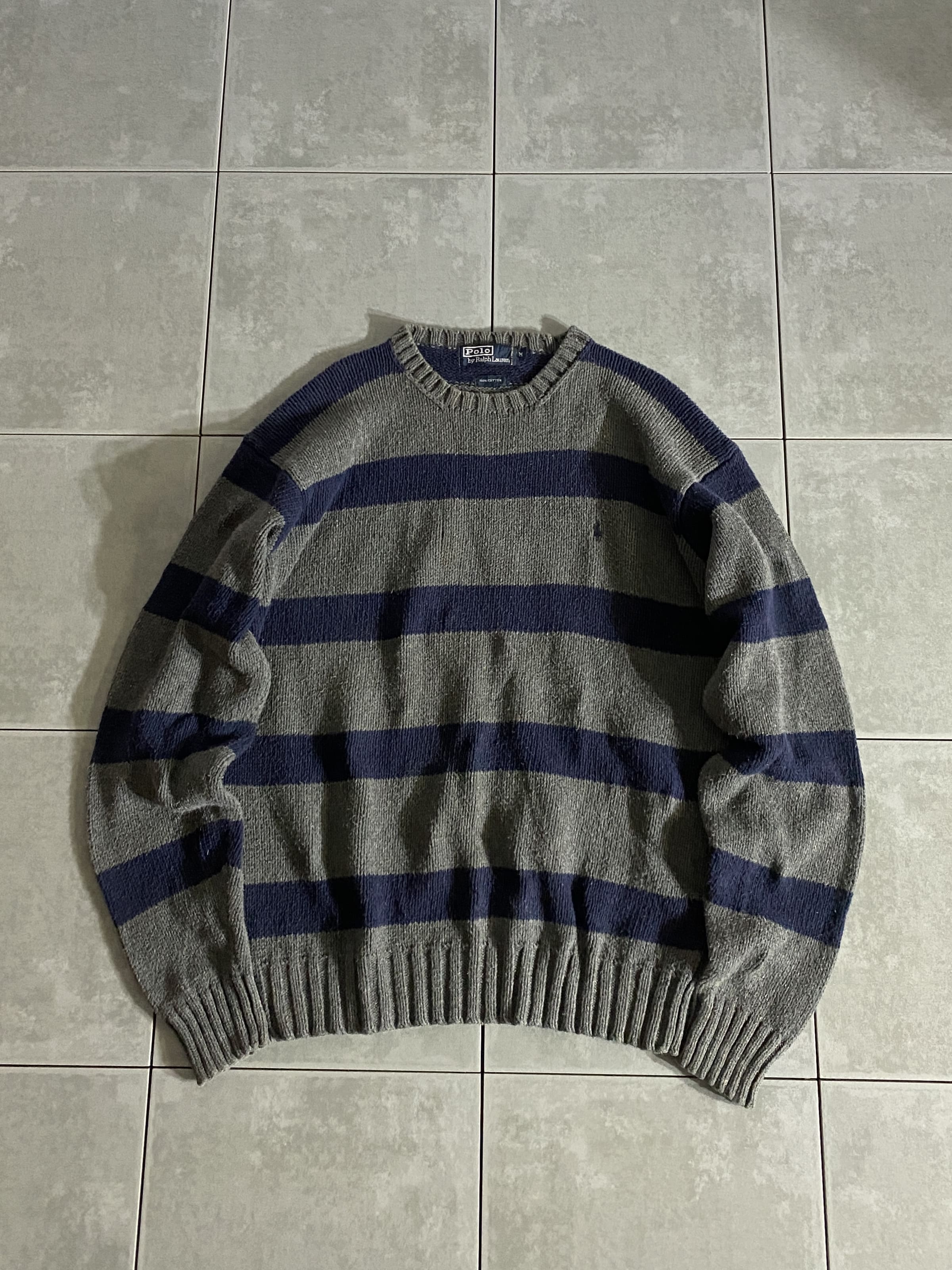 Polo Ralph Lauren

【Polo Ralph Lauren】90s Cotton Knit Sweater

カラー：グレー

サイズ：M
着丈：約64cm　身幅：約58cm　肩幅：約54cm　袖丈：約64cm

素材：コットン100％

90年代、ラルフローレンのコットンニット。

グレー、ネイビーのボーダーで
左胸にポニーの刺繍が施されています。

中にシャツを挟んだり、一枚で着てスラックスに
レザーシューズで綺麗にまとめるのも良し。

デニムにスニーカーでカジュアルに合わせても
良い感じです。

バリエーションも様々で、飽きのこない楽しめる一着です。

※フロント中央、若干汚れがございます。

※画像の程度とは若干異なる場合がございますので予めご了承下さい。
(キズ、へこみ、汚れ、穴あき、ほつれ、文字書入れ(名前、ナンバー)など