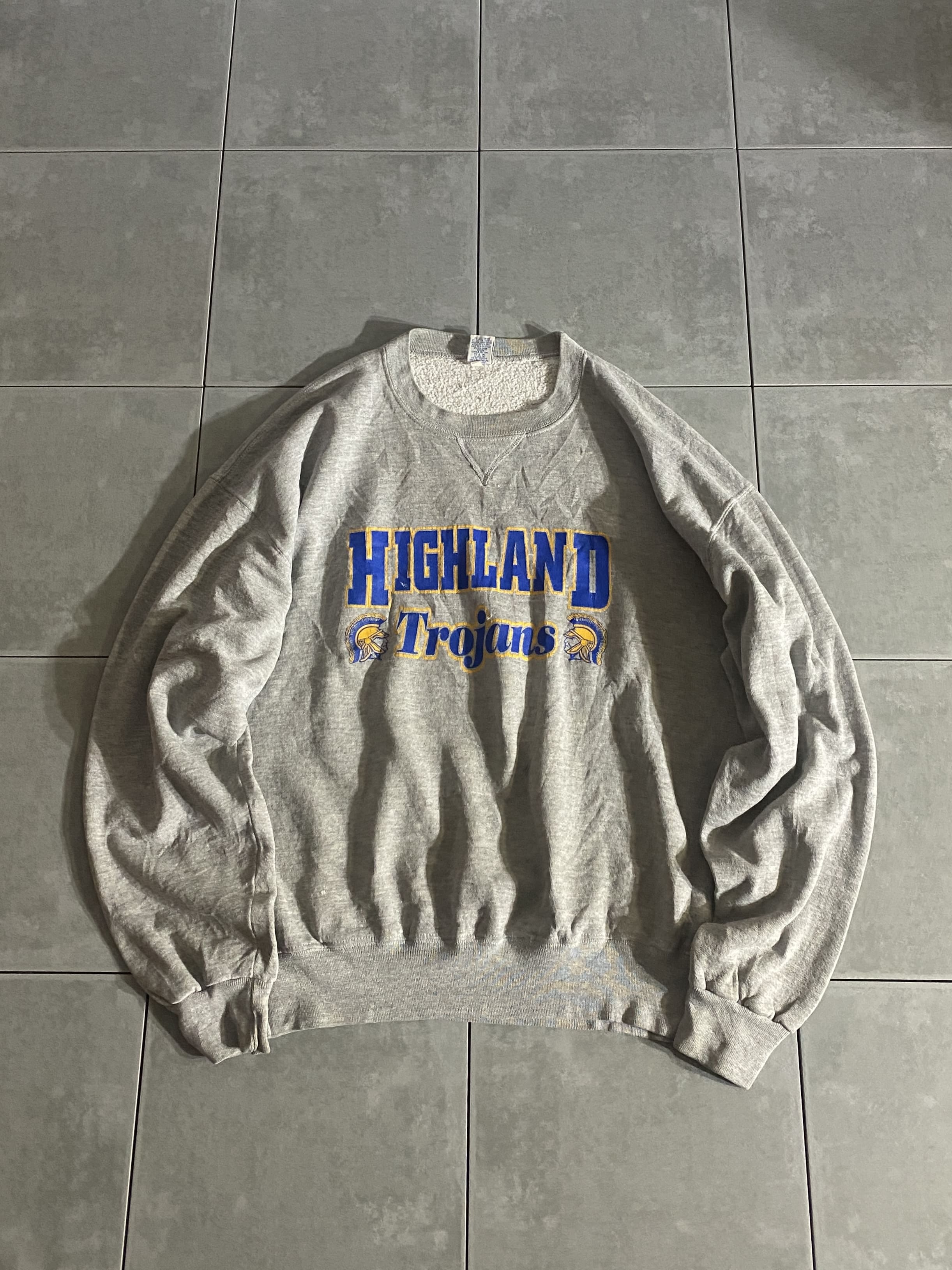 Russell Athletic

【Russell Athletic】90s HIGHLAND Trojans Sweatshirt

カラー：グレー

サイズ：XL
着丈：約67cm　身幅：約65cm　肩幅：約66cm　袖丈：約62cm

素材：53％ポリエステル　47％コットン

Russell Athleticのスウェットシャツ。

使い勝手の良いグレーボディに、
ブルー×イエローの配色抜群プリント。

身幅が広く、バランスの取りやすいシルエットです。

所々ペンキのような白い汚れがありますが
それも相まって男臭く、雑に着用できる一着です。

※首元や、肩など薄汚れございます。

※画像の程度とは若干異なる場合がございますので予めご了承下さい。
(キズ、へこみ、汚れ、穴あき、ほつれ、文字書入れ(名前、ナンバー)など

