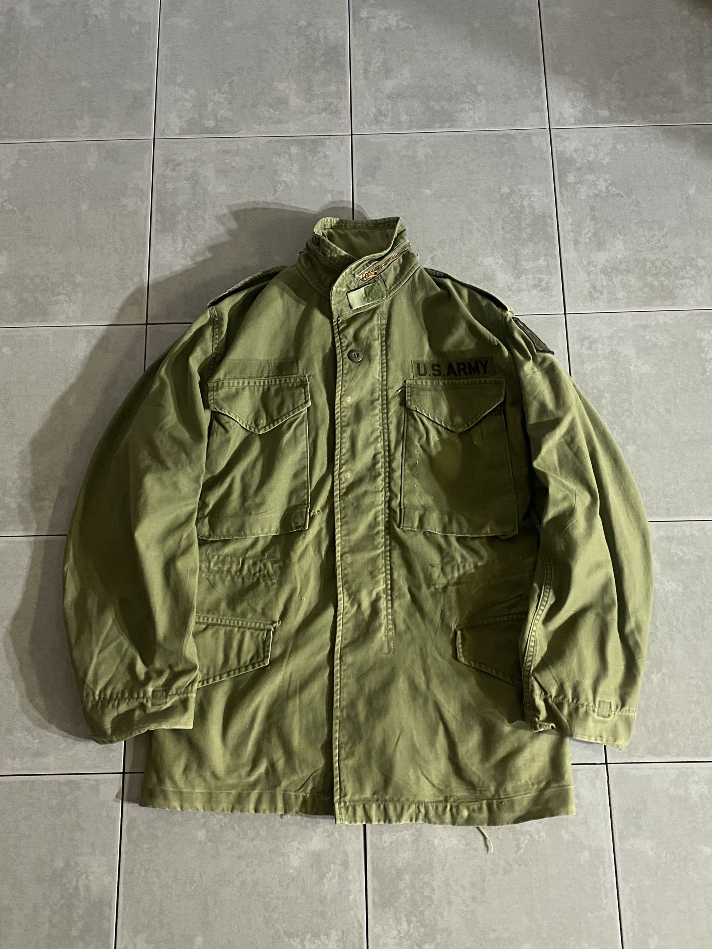 米軍放出品

M-65 Field Jacket 3rd Model

カラー：OD

サイズ：不明
着丈：約74cm　身幅：約50cm　肩幅：約45cm　袖丈：約60cm

素材：コットン　ナイロン

軍が開発したミリタリーアイテムの中で最高傑作ともいえる
M-65 Field Jacket。

アルミジップからブラスジップに変わった
3rd Model。

ミリタリーを語る上で外せないアイテムです。

ミリタリーは男臭くて、
着込まれたヤレ感があってこそ。

ODは放出がなく年々希少価値が上がっているので
今のうちに買っておくのがオススメです。

※ジッパーの引き手、取れて無くなっていますが
スナップボタンで開閉できますので着用に問題はございません。

※所々、穴あきございます。

※タグの印字は全て消えており、取れかけています。

※画像の程度とは若干異なる場合がございますので予めご了承下さい。
(キズ、へこみ、汚れ、穴あき、ほつれ、文字書入れ(名前、ナンバー)など

