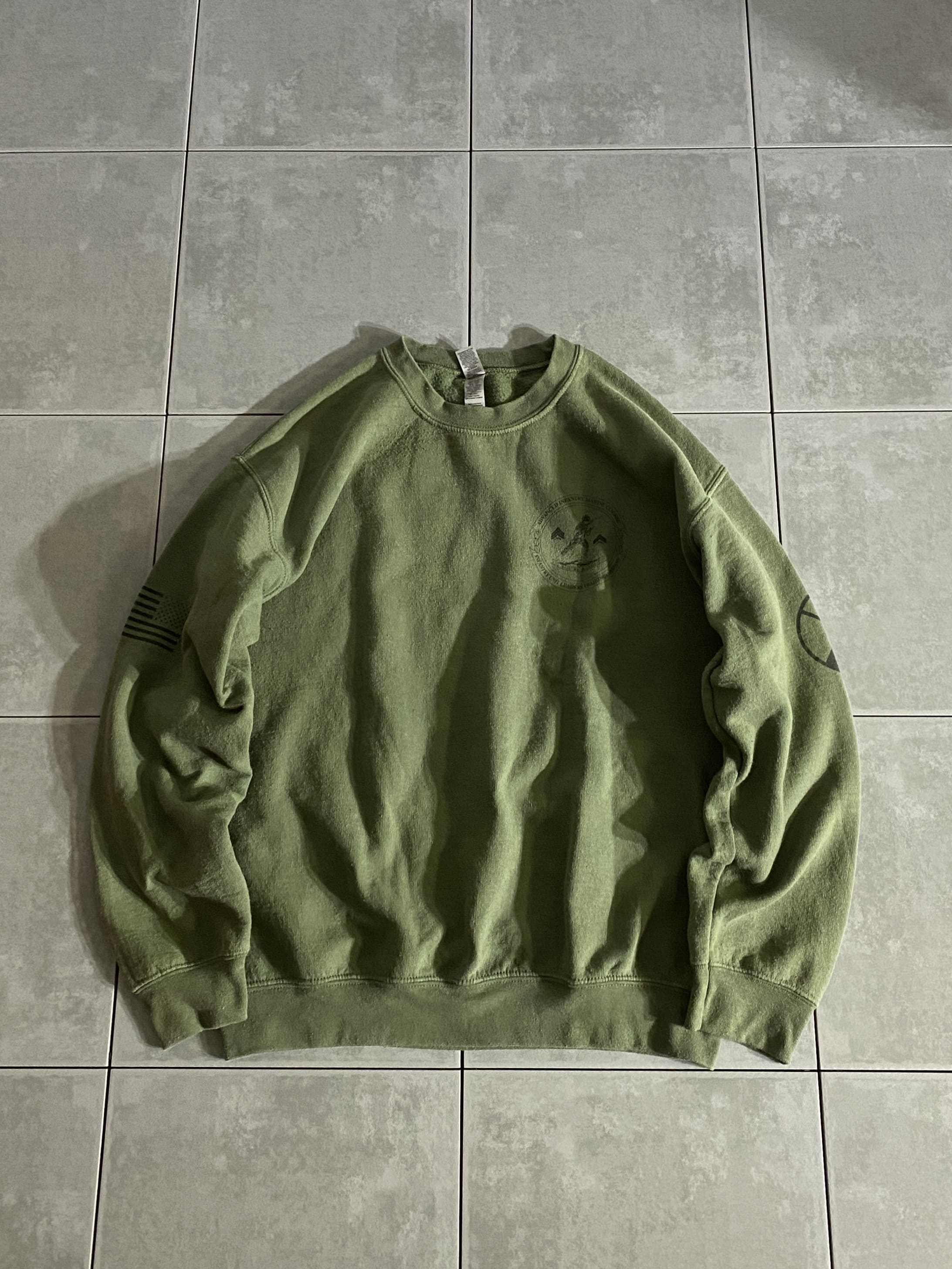 GILDAN

【GILDAN】Military Sweatshirt

【カラー】OD

【サイズ】M
着丈：約63cm　身幅：約56cm　肩幅：約53cm　袖丈：約56cm

【素材】コットン50％　ポリエステル50％

GILDANボディーのスウェットシャツ。

ODカラーにプリントのデザインが
いかにもミリタリーな一着。

普段着はもちろん、部屋着などにも使えるアイテムです。

※画像の程度とは若干異なる場合がございますので予めご了承下さい。
(キズ、へこみ、汚れ、穴あき、ほつれ、文字書入れ(名前、ナンバー)など