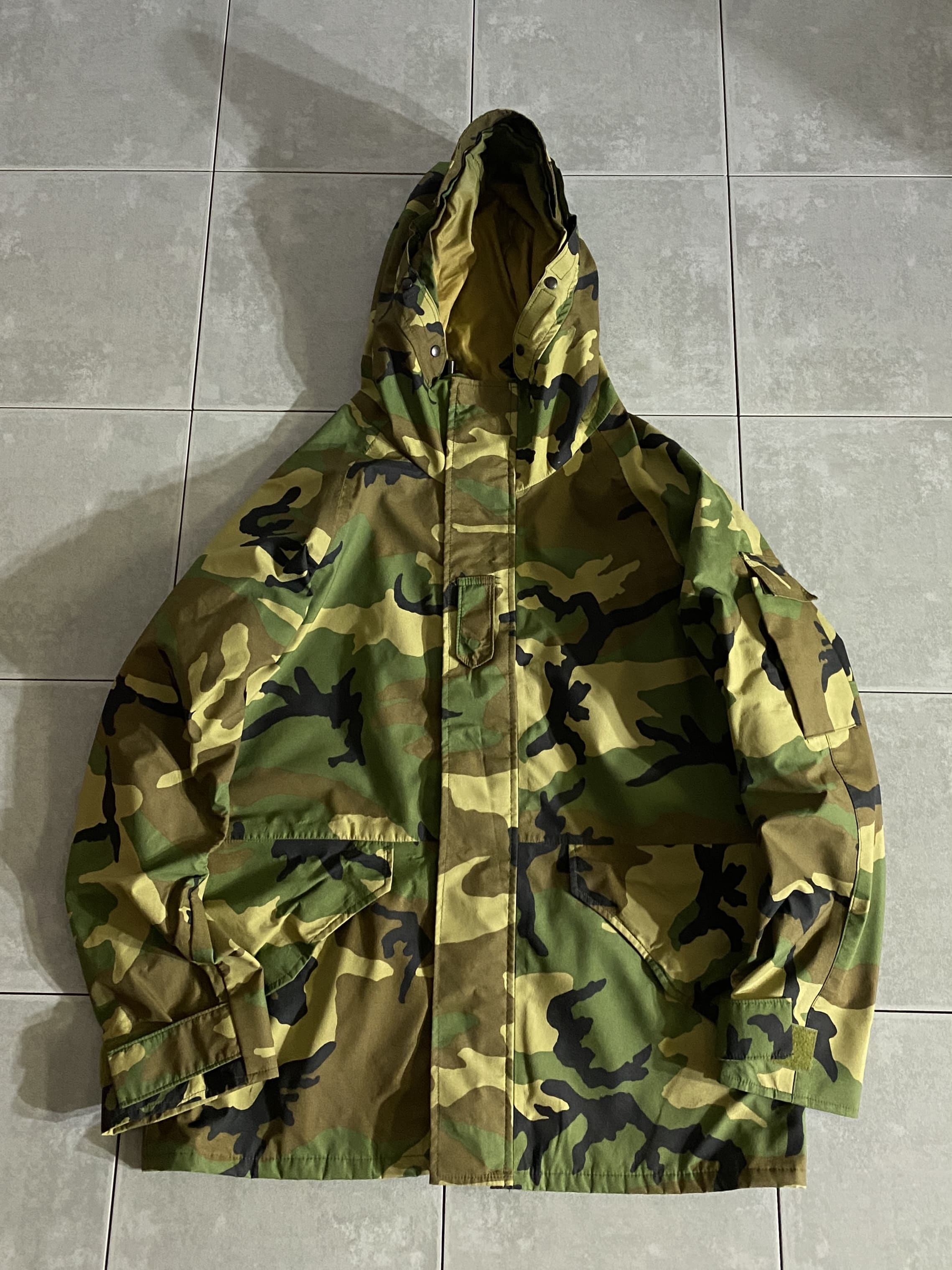 米軍放出品

PARKA COLD WEATHER CAMOUFLAGE

【カラー】WOODLAND

【サイズ】M-R
着丈：約75cm　身幅：約64cm　裄丈：約90cm　

【素材】ナイロン100％

防水性、保温性、耐久性を兼ね備えた
ミリタリーアイテムの最高峰。

収納は左右のフラップポケットや
左腕のユーティリティポケット。

脇下にはベンチレーションジップが設けられており、
着たままでの体温調節が可能です。

ラグランスリーブなので、広い可動域で動きやすい
デザインになっております。

夏は高性能レインウェア、その他はアウターとして
年中使用できる抜群のアイテムです。

※ジッパー不良の為、スナップボタンでの開閉となります。

※1番下のボタン、オスメスくっ付いた状態なので使用できません。

※画像の程度とは若干異なる場合がございますので予めご了承下さい。
(キズ、へこみ、汚れ、穴あき、ほつれ、文字書入れ(名前、ナンバー)など
