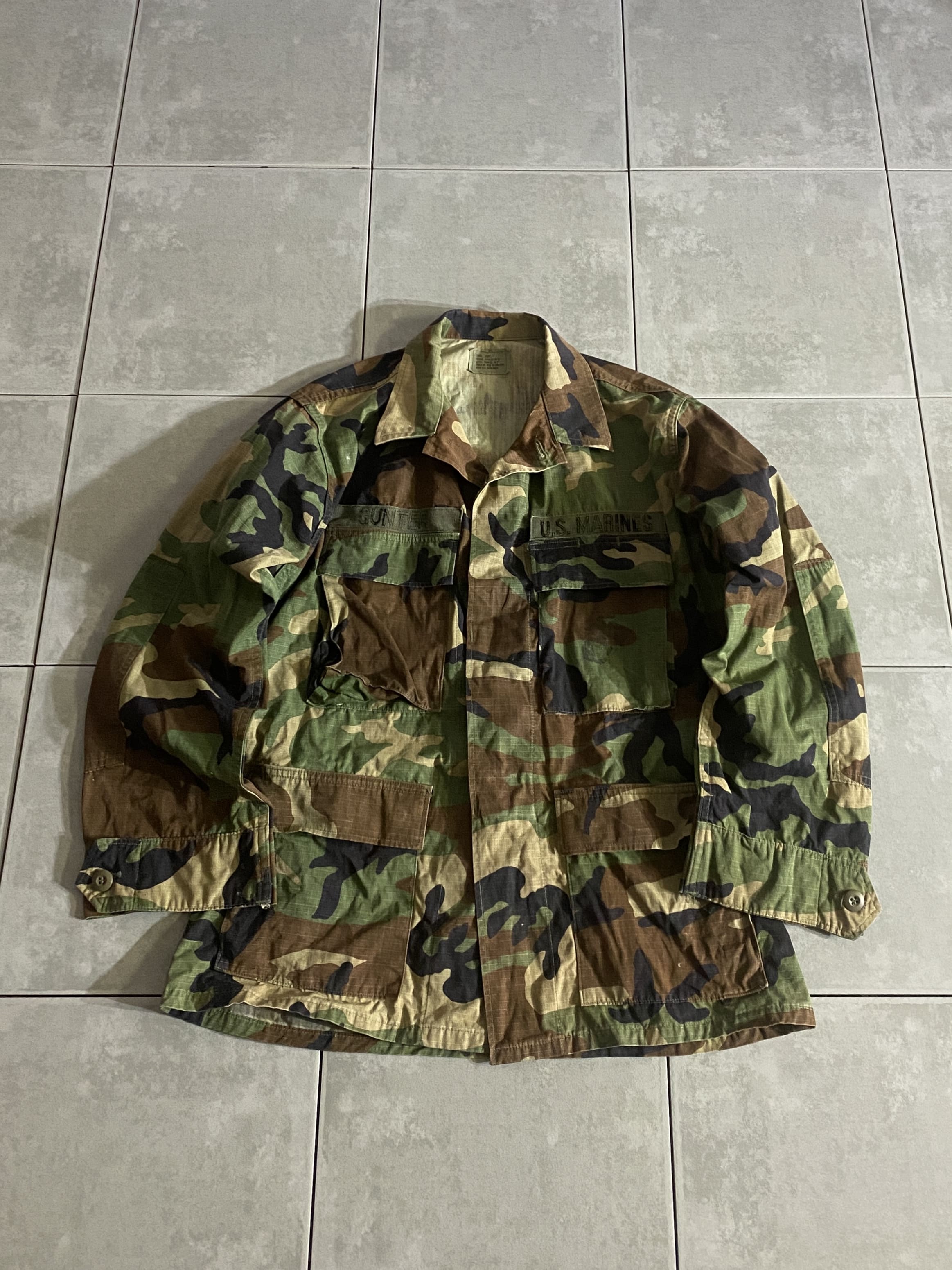 米軍放出品

HOT WEATHER BDU JACKET

【カラー】WOODLAND

【サイズ】S-S
着丈：約71cm　身幅：約56cm　肩幅：約45cm　袖丈：約58cm

【素材】コットン50％　ナイロン50％

リップストップ生地

ウッドランドのHOT WEATHER BDUジャケット。

広範な気候と温度に対応するように開発された
薄手生地のジャケットです。

フロントに4つのポケット、
USMCのロゴが薄らプリントされております。

シャツジャケットのような感覚で、
真冬以外の3シーズン着用いただけます。

※画像の程度とは若干異なる場合がございますので予めご了承下さい。
(キズ、へこみ、汚れ、穴あき、ほつれ、文字書入れ(名前、ナンバー)など