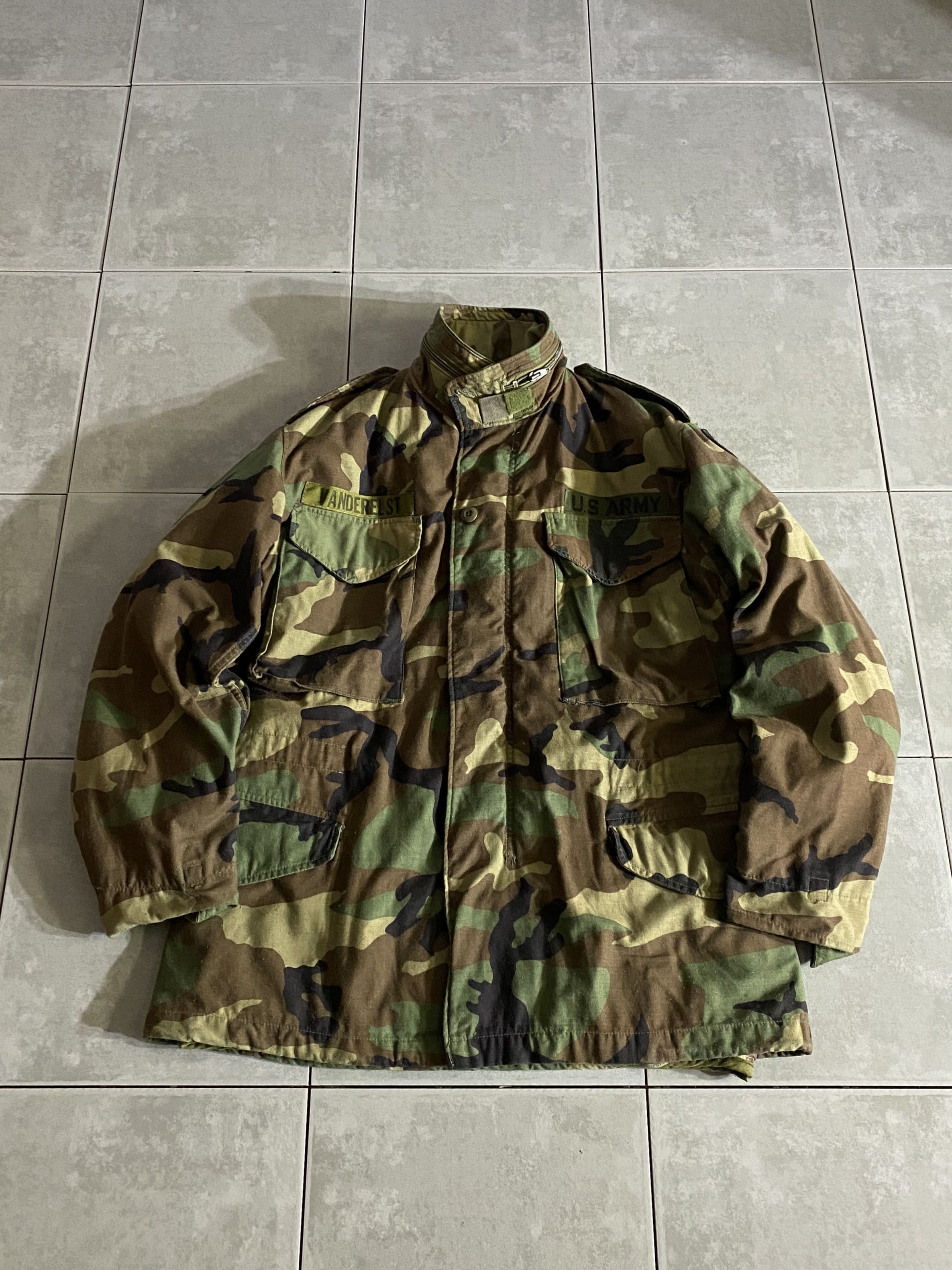 米軍放出品

M-65 Field Jacket ライナー付き

【カラー】WOODLAND

【サイズ】S-S
着丈：約73cm　身幅：約55cm　肩幅：約50cm　袖丈：約59cm

【素材】コットン50％　ナイロン50％

軍が開発したミリタリーアイテムの中で最高傑作ともいえる
M-65 Field Jacket。

ミリタリーを語る上で外せないアイテムです。

収納式フード、肩にはエポレット付きで
フロント部分はジッパーとスナップボタンで開閉できます。

目立ったダメージもない、ライナー付きのグッドコンディションです。

※ライナーは実物ではございません。

※画像の程度とは若干異なる場合がございますので予めご了承下さい。
(キズ、へこみ、汚れ、穴あき、ほつれ、文字書入れ(名前、ナンバー)など
