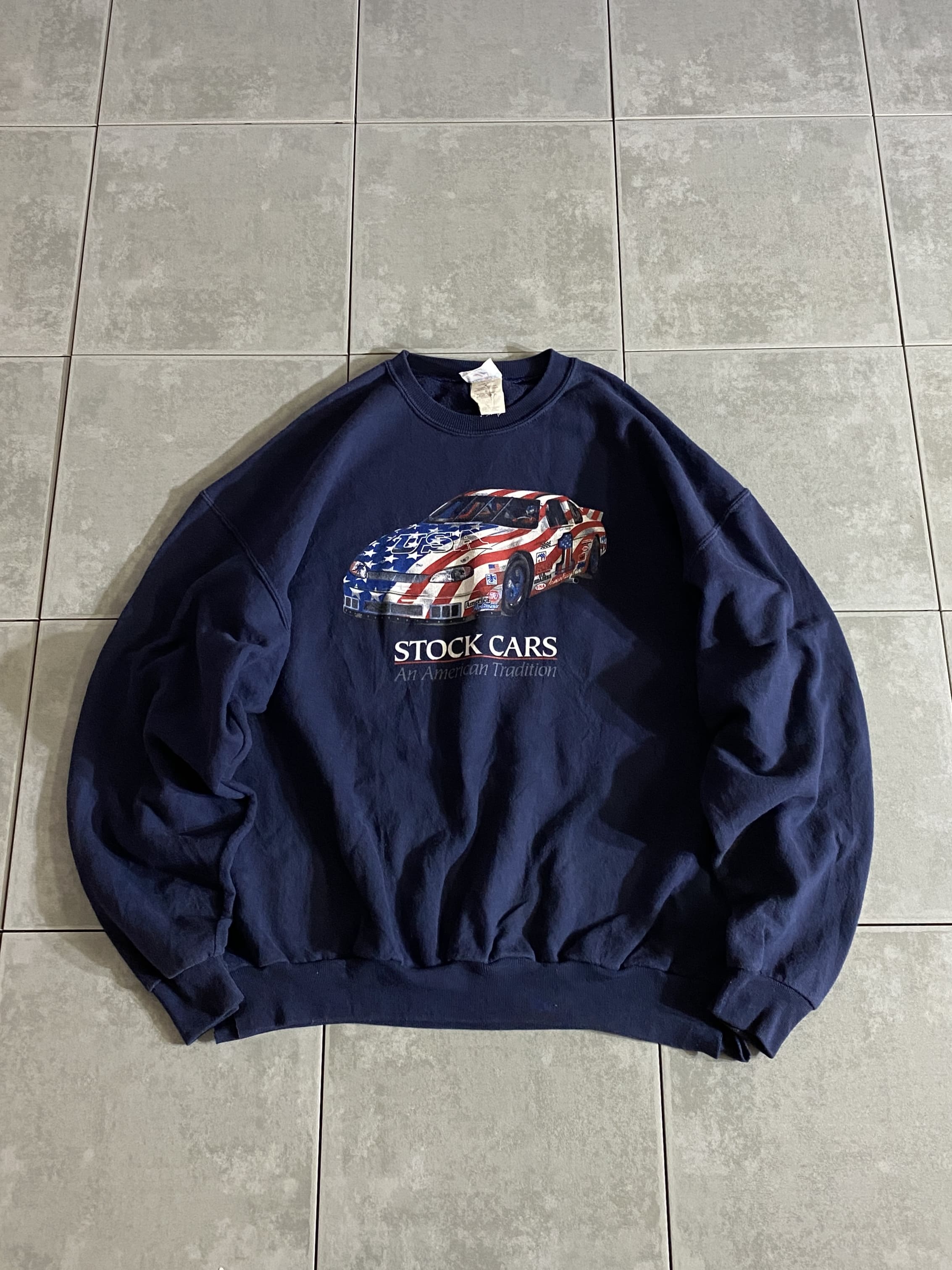 JERZEES

【JERZEES】90s STOCK CARS Sweatshirt

【カラー】XL
着丈：約65cm　身幅：約66cm　肩幅：約64cm　袖丈：約58cm

【素材】コットン50％　ポリエステル50％

JERZEESのスウェットシャツ。

フロントにはアメリカ国旗のストックカーのプリント。

濃紺のネイビーボディーとの相性もバッチリです。

サイズはXLと少し大きめなのでゆったり着用できます。

※裾の両端、意図的にハサミで切られています。

※画像の程度とは若干異なる場合がございますので予めご了承下さい。
(キズ、へこみ、汚れ、穴あき、ほつれ、文字書入れ(名前、ナンバー)など

