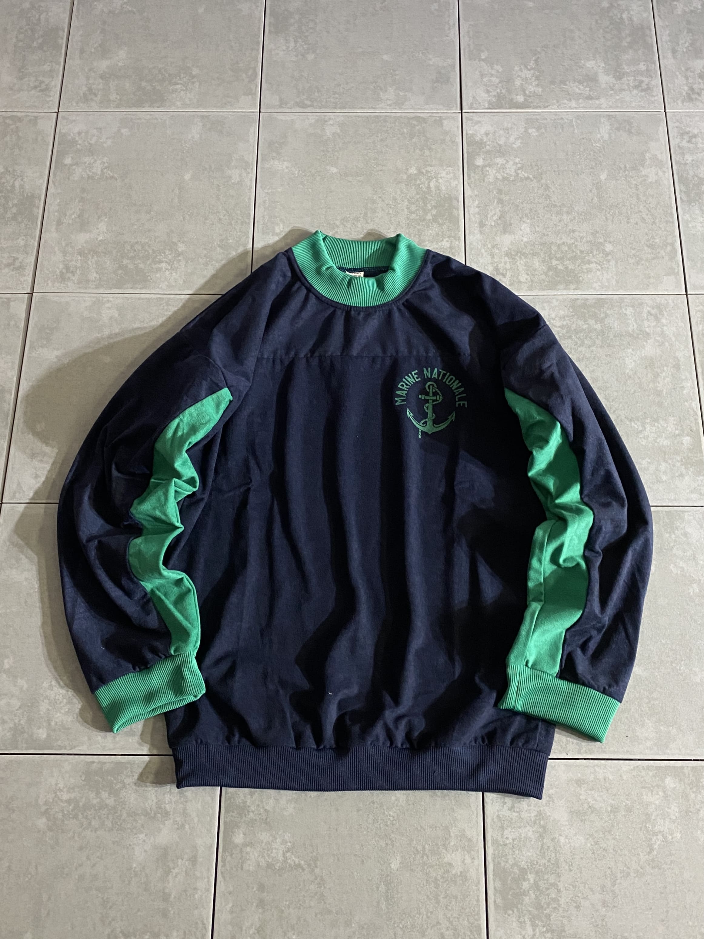 DEAD STOCK

フランス海軍 VELVETEEN Training Sweatshirt

【カラー】ネイビー/グリーン

【サイズ】88M
着丈：約70cm　身幅：約58cm　肩幅：約60cm　袖丈：約54cm

【素材】コットン　ポリエステル

フランス海軍でトレーニングやウォームアップなどでの使用を目的に
1990年代後半に採用されたスウェットシャツ。

別珍という素材を使用したトレーニングスウェットシャツで、
鮮やかなネイビーとグリーンのメリハリの効いたバイカラーです。

配色切り替えがアクセントになり、1枚で着ても秋冬には
レイヤードとしても使える色使いが絶妙なバランスです。

別珍素材のスウェットはかなり珍しいデザインで、
ファッション性が高く、カジュアルなスタイルにもハマるアイテムです。

※画像の程度とは若干異なる場合がございますので予めご了承下さい。
(キズ、へこみ、汚れ、穴あき、ほつれ、文字書入れ(名前、ナンバー)など
