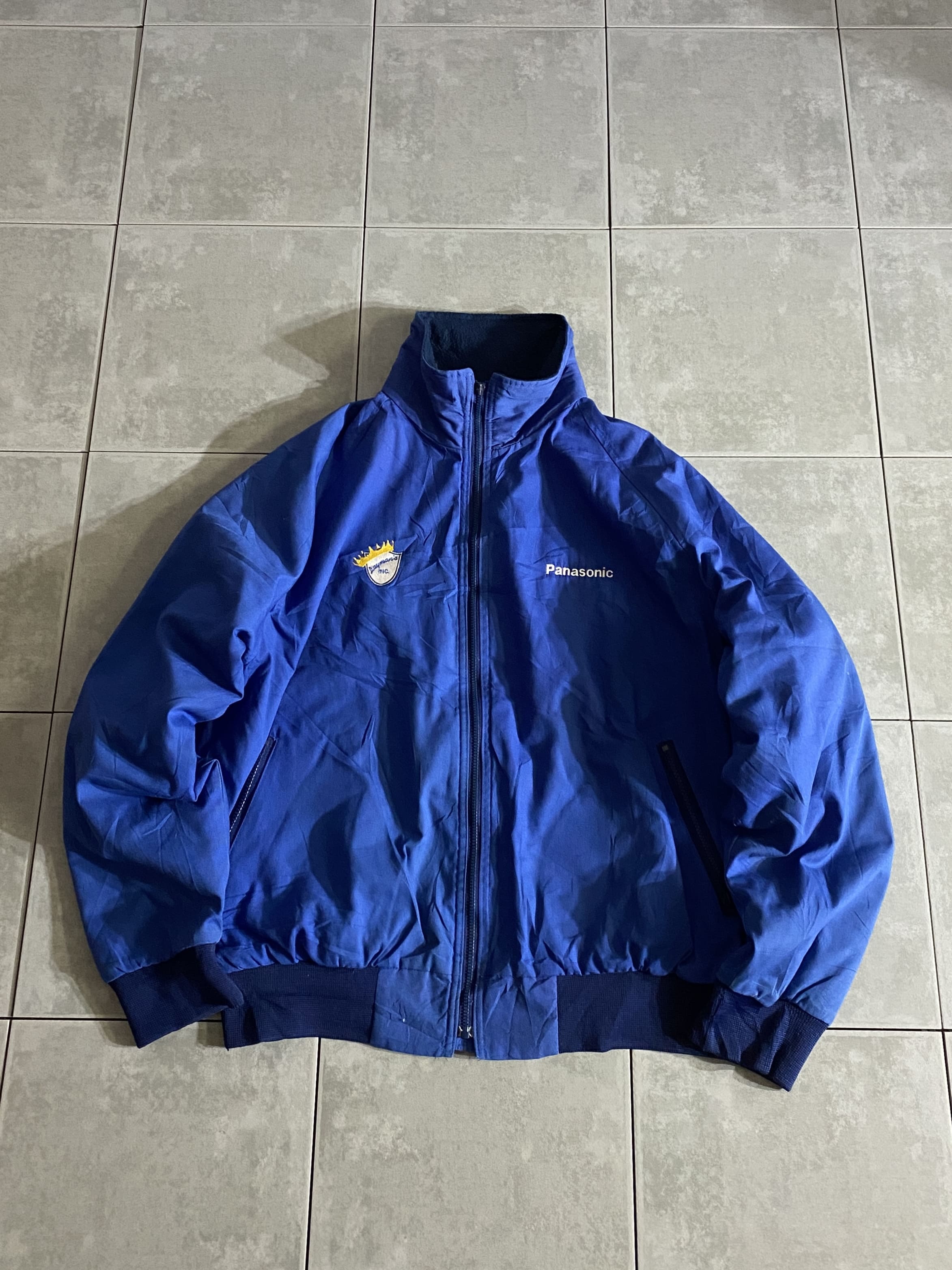 HILTON

【HILTON】90s Panasonic Track Jacket Made in USA

【カラー】ブルー

【サイズ】不明
着丈：約66cm　身幅：約72cm　裄丈：約95cm　

【素材】ポリエステル65％　コットン35％
　
90年代、HILTONのトラックジャケット。

古着の中でも人気の高い企業モノ。

両胸にワンポイント刺繍の無駄のないシンプルなデザイン。

良い感じのブルーにサイズ感、シルエット文句なしの1着です。

※ジッパーの引き手取れておりますのでクリップを通してます。

※袖、若干薄汚れございます。

※画像の程度とは若干異なる場合がございますので予めご了承下さい。
(キズ、へこみ、汚れ、穴あき、ほつれ、文字書入れ(名前、ナンバー)など