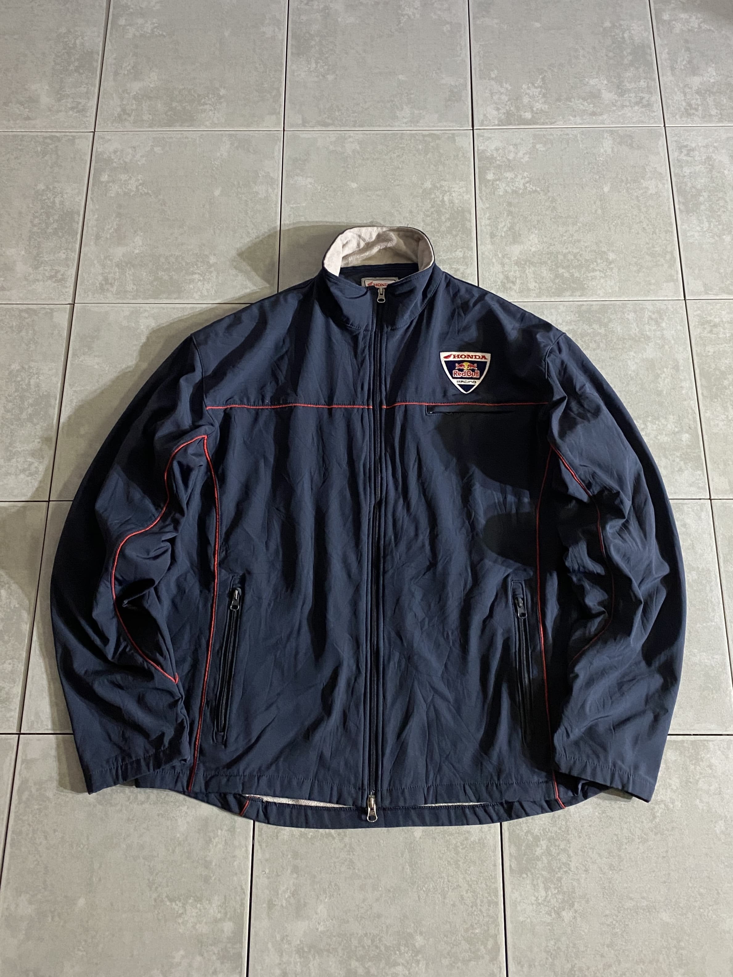 Redbull

Redbull HONDA Racing Track Jacket 

【カラー】ネイビー

【サイズ】2XL
着丈：約76cm　身幅：約70cm　肩幅：約57cm　袖丈：約64cm

【素材】ポリエステル100％

Redbull×HONDAの豪華な1着。

全体的にシンプルながらも、
見ただけでわかるカッコいいデザイン。

合わせやすいネイビーカラーなので、
コーデが組みやすいのもポイント。

目立ったダメージもなく、まだまだ楽しんでお使いいただけます。

※画像の程度とは若干異なる場合がございますので予めご了承下さい。
(キズ、へこみ、汚れ、穴あき、ほつれ、文字書入れ(名前、ナンバー)など