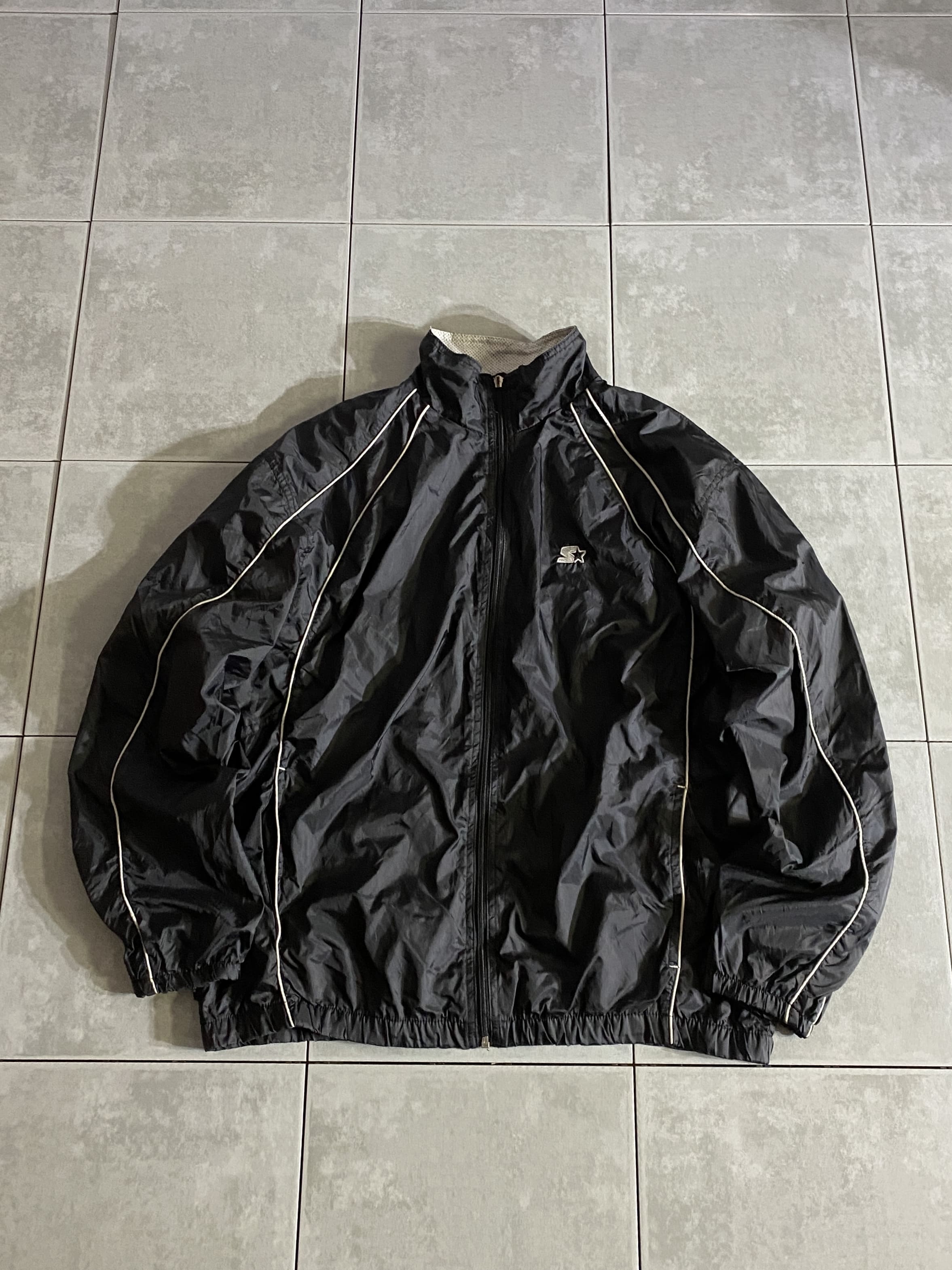 STARTER

【STARTER】Nylon Jacket

【カラー】ブラック

【サイズ】M
着丈：約67cm　身幅：約60cm　肩幅：約55cm　袖丈：約61cm

【素材】ナイロン100％

STARTERのナイロンジャケット。

左胸に刺繍ロゴの至ってシンプルな1着。

普段使いはもちろん、運動時などにも着用でき
様々なシーンで使用できます。

使い勝手の良いアイテムです。

※ジッパーの引き手取れております。
スライダーは残っていますが、
引き手を通す部分も取れております。

※画像の程度とは若干異なる場合がございますので予めご了承下さい。
(キズ、へこみ、汚れ、穴あき、ほつれ、文字書入れ(名前、ナンバー)など

