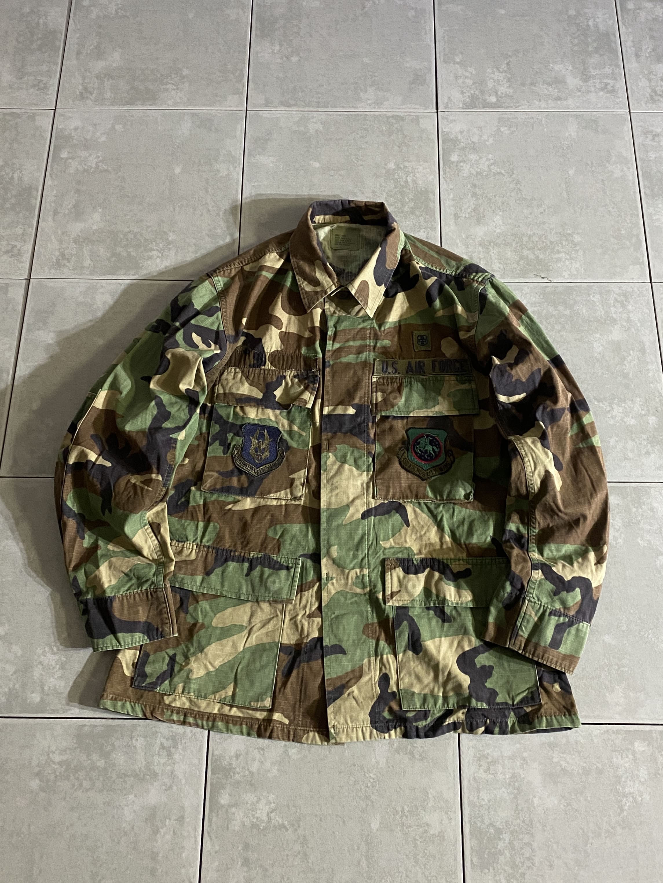 米軍放出品

HOT WEATHER BDU JACKET

【カラー】WOODLAND

【サイズ】S-S
着丈：約71cm　身幅：約52cm　肩幅：約 45cm　袖丈：約57cm

【素材】コットン50％　ナイロン50％

リップストップ生地

ウッドランドのHOT WEATHER BDUジャケット。

広範な気候と温度に対応するように開発された
薄手生地のジャケットです。

フロントに4つのポケットがございます。

シャツジャケットのような感覚で、
真冬以外の3シーズン着用いただけます。

※画像の程度とは若干異なる場合がございますので予めご了承下さい。
(キズ、へこみ、汚れ、穴あき、ほつれ、文字書入れ(名前、ナンバー)など
