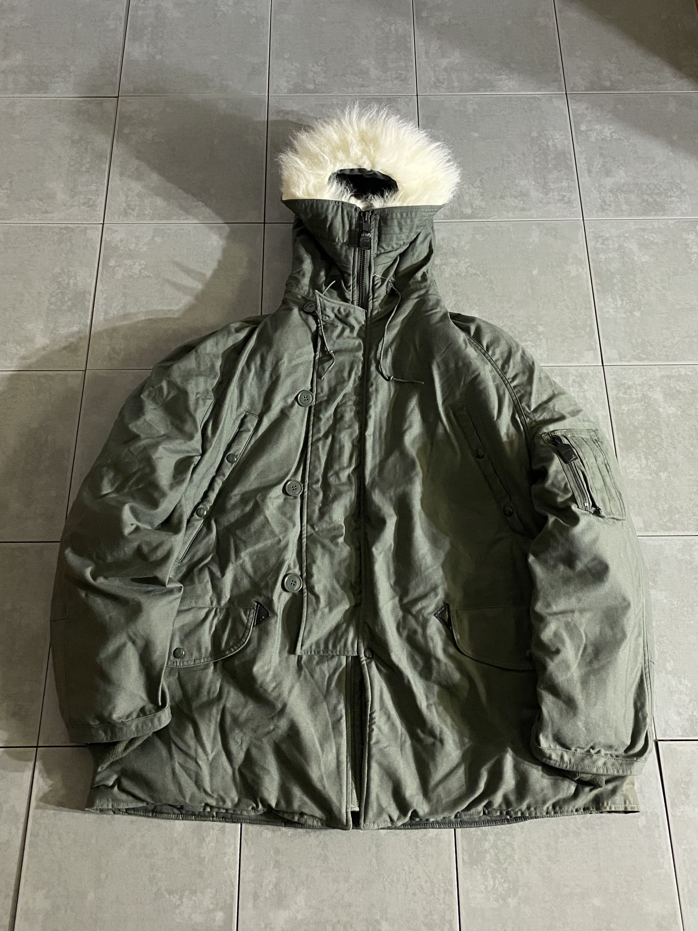 米軍放出品

N-3B Flight Jacket

【カラー】SAGE

【サイズ】XL
着丈：約89cm　身幅：約75cm　裄丈：約97cm　

【素材】コットン

ミリタリーウェアーの代表格、N-3B。

極寒地で着用出来るように作られており、
フード部分の毛は吹雪でも前が見えるように工夫され、
表生地は風を通さないように、そして中綿は保温に
良い素材が使われています。

手袋着用で手を入れることが多い為　
ポケット、ボタンは大きめで、全て機能的に使いやすく
工夫されています。

ミリタリー界最高峰の優れもの、コレクションなどにも
オススメです。

持っていて損はないアイテムです。

※バック、大きめのシミがございます。
その他は比較的グッドコンディションです。

※画像の程度とは若干異なる場合がございますので予めご了承下さい。
(キズ、へこみ、汚れ、穴あき、ほつれ、文字書入れ(名前、ナンバー)など
