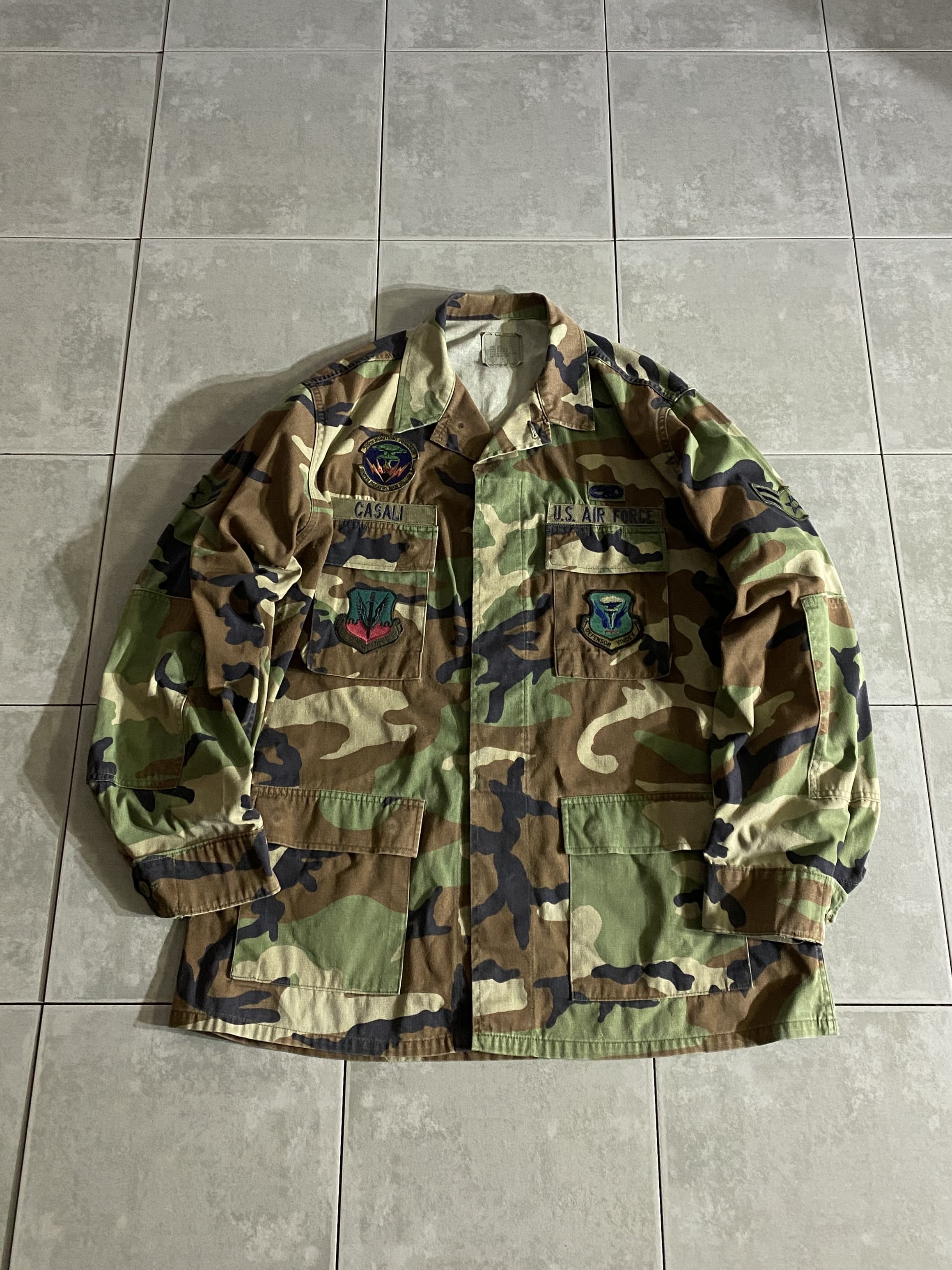 米軍放出品

80s BDU WOODLAND CAMO JACKET 中期型

【カラー】WOODLAND

【サイズ】L-L
着丈：約82cm　身幅：約65cm　肩幅：約50cm　袖丈：約66cm

【素材】コットン50％　ナイロン50％

ノンリップ

1981年より約30年以上にわたり全米軍で使用された
ウッドランドのBDUジャケット。

中期型は1984年頃から1995年頃まで生産されたモデルで、
胸ポケットのマチが外側に設けられており
襟の形状が中期型以降は小さくなっております。

新品には出せない風合いのよい生地のアタリやムラ感は
USEDならではです。

年々希少価値が上がり、入手困難になっている
オススメアイテムの1つです。

※画像の程度とは若干異なる場合がございますので予めご了承下さい。
(キズ、へこみ、汚れ、穴あき、ほつれ、文字書入れ(名前、ナンバー)など
