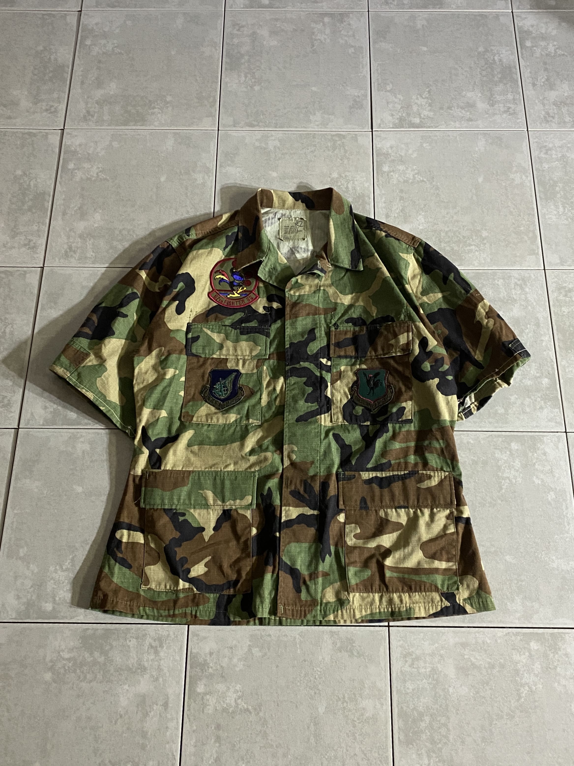 米軍放出品

HOT WEATHER BDU JACKET S/S Shirt(Remake) 

【カラー】WOODLAND

【サイズ】M-S
着丈：約72cm　身幅：約60cm　肩幅：約47cm　袖丈：約28cm

【素材】コットン50％　ナイロン50％

リップストップ生地

ウッドランドのHOT WEATHER BDUジャケット。

広範な気候と温度に対応するように開発された
薄手生地のジャケットです。

半袖シャツにリメイクされているので、
ジャケットとは違った楽しみ方ができるのがポイント。

パッチ付きで、オリジナル感のあるオススメアイテムです。

※フラップポケット、糸で縫われて開かないようになっております。

※画像の程度とは若干異なる場合がございますので予めご了承下さい。
(キズ、へこみ、汚れ、穴あき、ほつれ、文字書入れ(名前、ナンバー)など