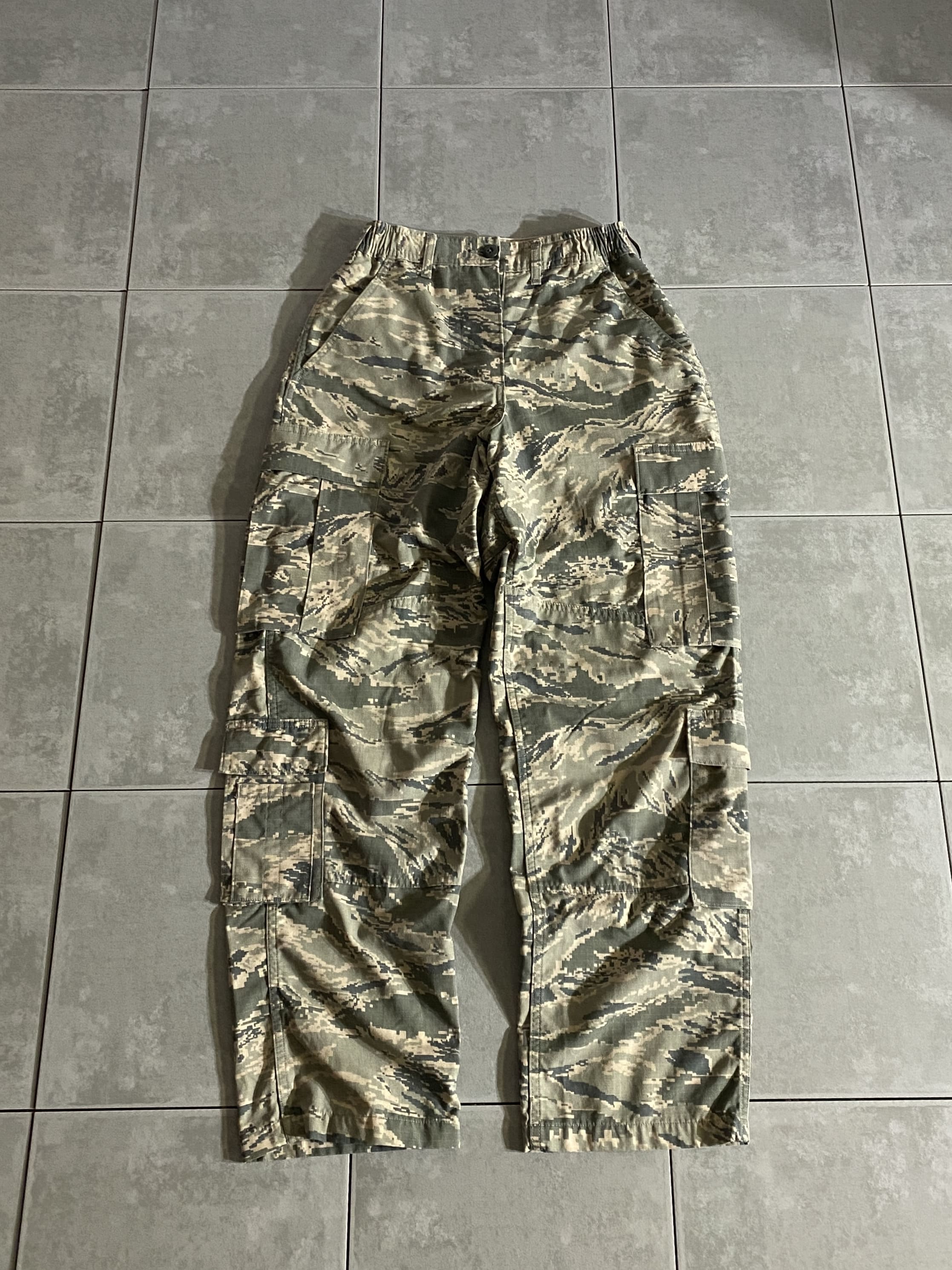 米軍放出品

U.S.AIR FORCE Womens Utility Cargo Pants

【カラー】ABU

【サイズ】不明
ウエスト：約66-72cm　股下：約74cm　
ワタリ：約32cm　総丈：約103cm

【素材】コットン50％　ナイロン50％

2007年より支給が開始し、2021年まで採用されていたABU。

U.S.AIR FORCE独自のデジタルタイガーストライプ、
女性用カーゴパンツです。

フロントはボタンフライ仕様で、両サイドがゴムで伸縮。

BDUパンツと同様に、膝部分の2重に補強された
ダブルニーとヒップ部分が特徴的なデザイン。

サイド、バック、カーゴポケットに加えて、
膝下にもポケットが付属した8ポケットデザインとなっております。

※フロントボタンフライ、上から2つめのボタンございません。

※画像の程度とは若干異なる場合がございますので予めご了承下さい。
(キズ、へこみ、汚れ、穴あき、ほつれ、文字書入れ(名前、ナンバー)など