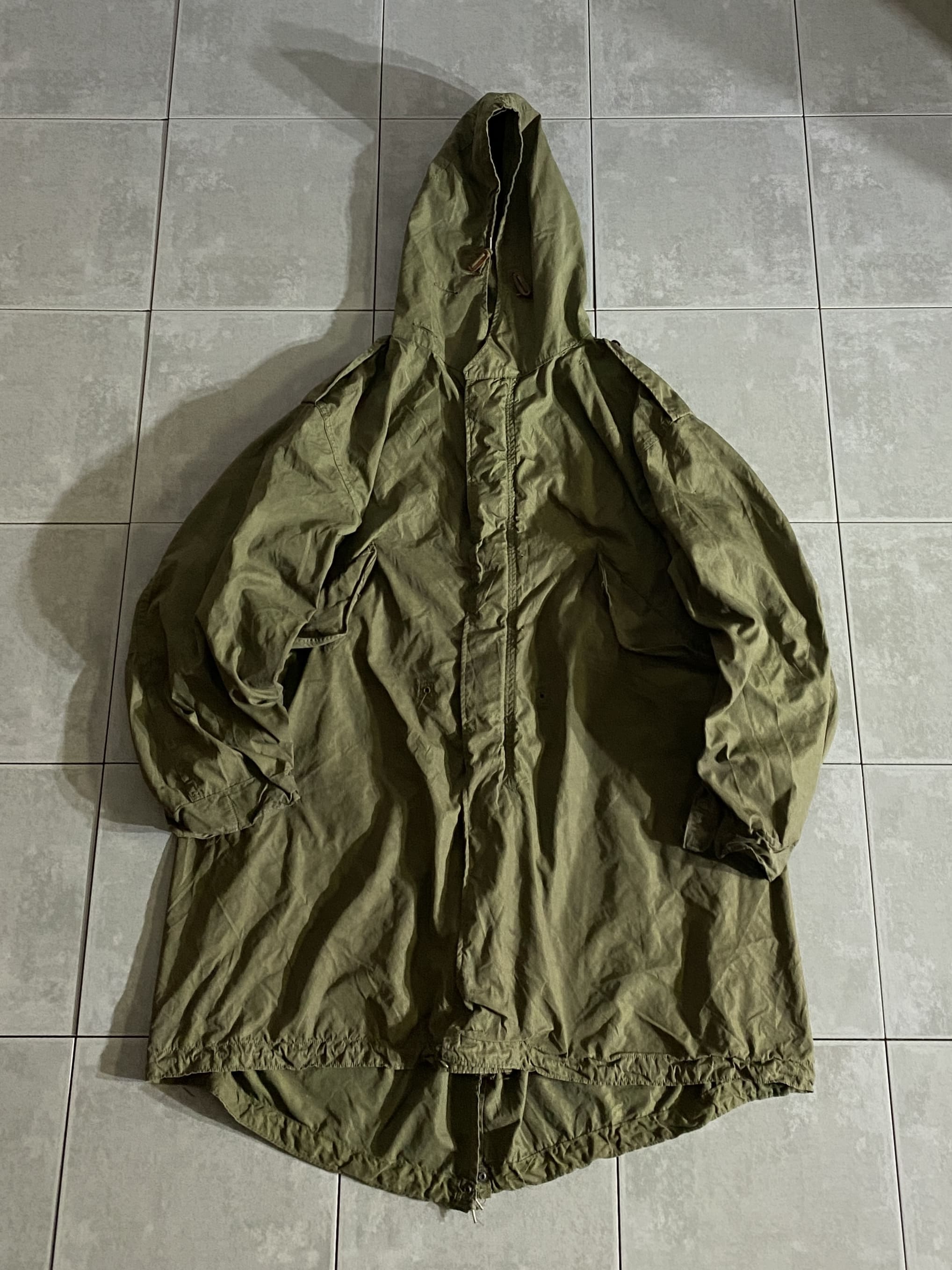 米軍放出品 実物

PARKA SHELL M-1951 後期型

【カラー】OD

【サイズ】M
着丈：約104cm　身幅：約73cm　肩幅：約60cm　袖丈：約61cm

【素材】コットン、ナイロン混紡オックスフォード

一般的にモッズコート、モッズパーカ、フィッシュテールなどと呼ばれる
M-51。

50年代から60年代にかけイギリスの若い労働者を中心に
流行した『モッズファッション』を好んだ人々『モッズ』。

彼らが好んで着た事から『モッズパーカー』と呼ばれています。

ヴィンテージ市場で状態の良いものを見つけることが困難な
希少性の高いモデルです。

フード一体型のデザインや肩に配されたエポレットのデザインが特徴。

USEDのコンディションですが、まだまだ楽しんで着用できる一枚。

現在に至るまで、半世紀以上に渡って愛され続ける
ミリタリージャケットの名作です。

※汚れや穴あき、左袖に大きな破れがございます。

※画像の程度とは若干異なる場合がございますので予めご了承下さい。
(キズ、へこみ、汚れ、穴あき、ほつれ、文字書入れ(名前、ナンバー)など
