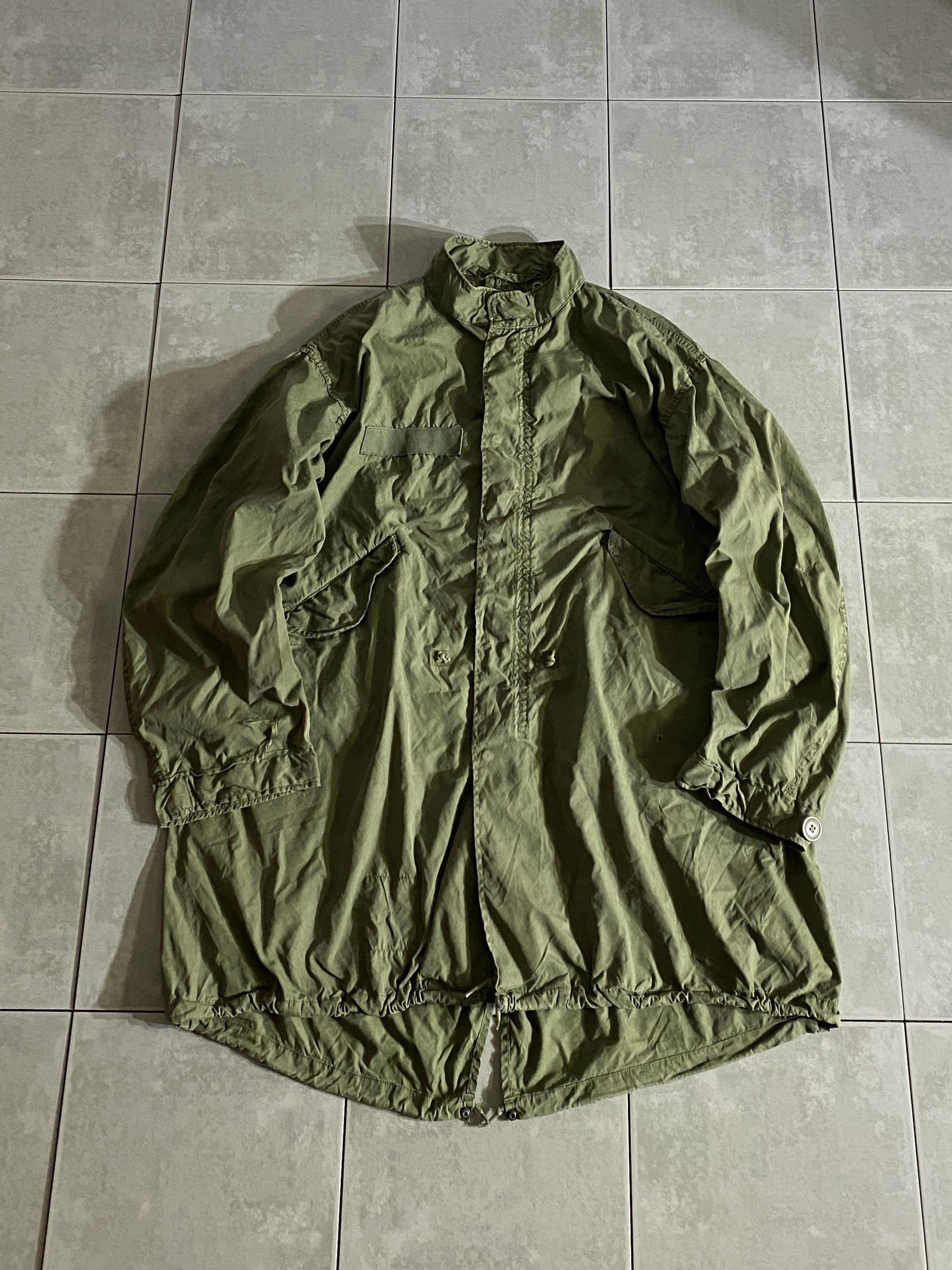 米軍放出品 実物

PARKA EXTREME COLD WEATHER M-65 PARKA

【カラー】OD

【サイズ】M-R
着丈：約101cm　身幅：約70cm　肩幅：約60cm　袖丈：約63cm

【素材】コットン、ナイロン混紡オックスフォード

1960年代後半からアメリカ地上軍に採用された
65年型極寒用野戦パーカー。

フラップの付いた大型のハンドポケット、フィッシュテール型の裾など、
基本的には前モデルのM-51パーカーを引き継ぐ形です。

M-51パーカーでは縫い付けであったフードが
M-65では脱着式に変更、肩のエポレットが省略されており、
裾のドローコードがゴムに変更されております。

ヴィンテージで状態の良いものを見つけることが難しくなってきている
アイテムの一つ。

特に目立った汚れなどもなく、まだまだ楽しんで着用できる一枚です。

※小さな穴あき、右袖に破れがございます。

※画像の程度とは若干異なる場合がございますので予めご了承下さい。
(キズ、へこみ、汚れ、穴あき、ほつれ、文字書入れ(名前、ナンバー)など


